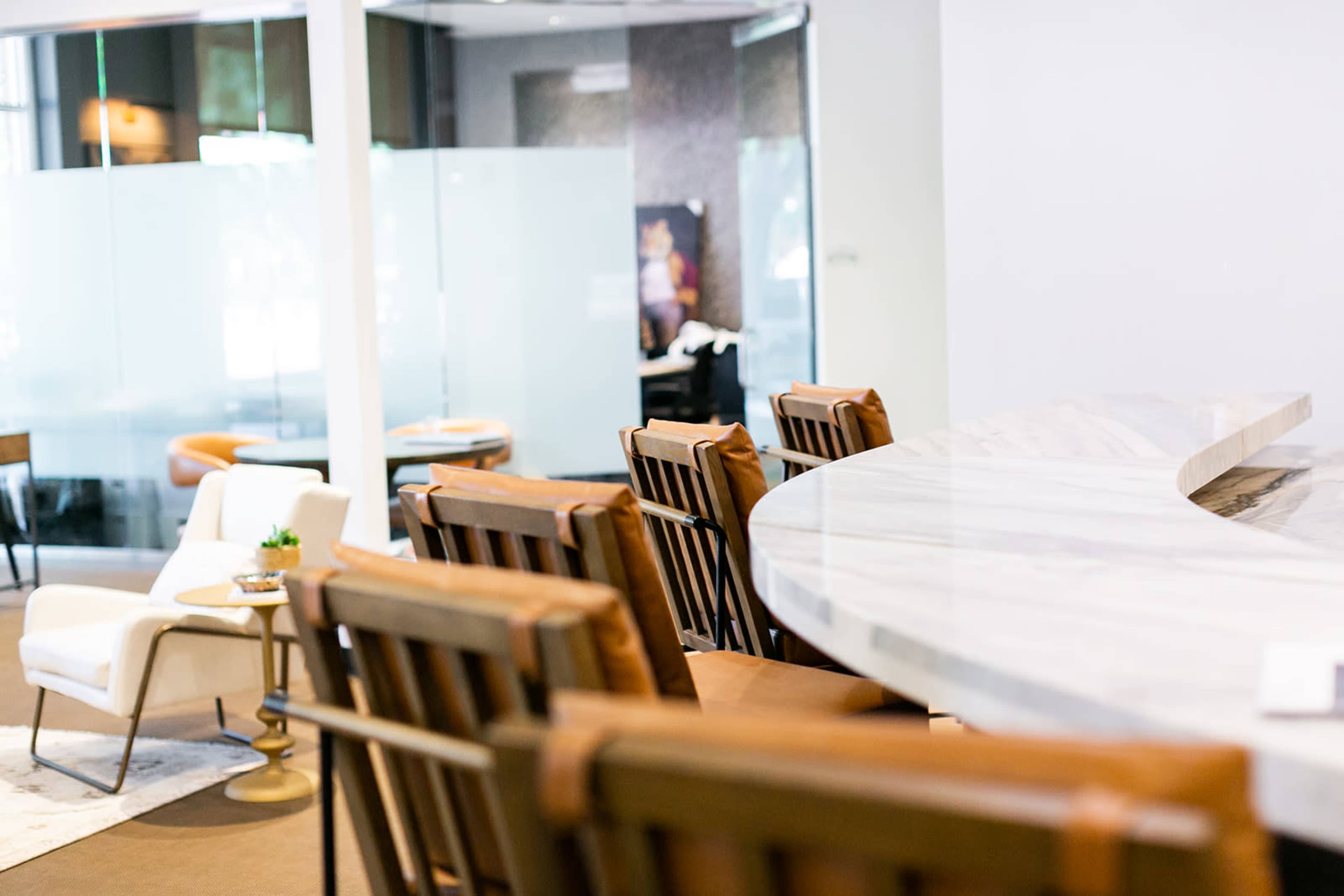 The image shows a modern reception area featuring a marble counter with several wooden chairs and a small table in front.