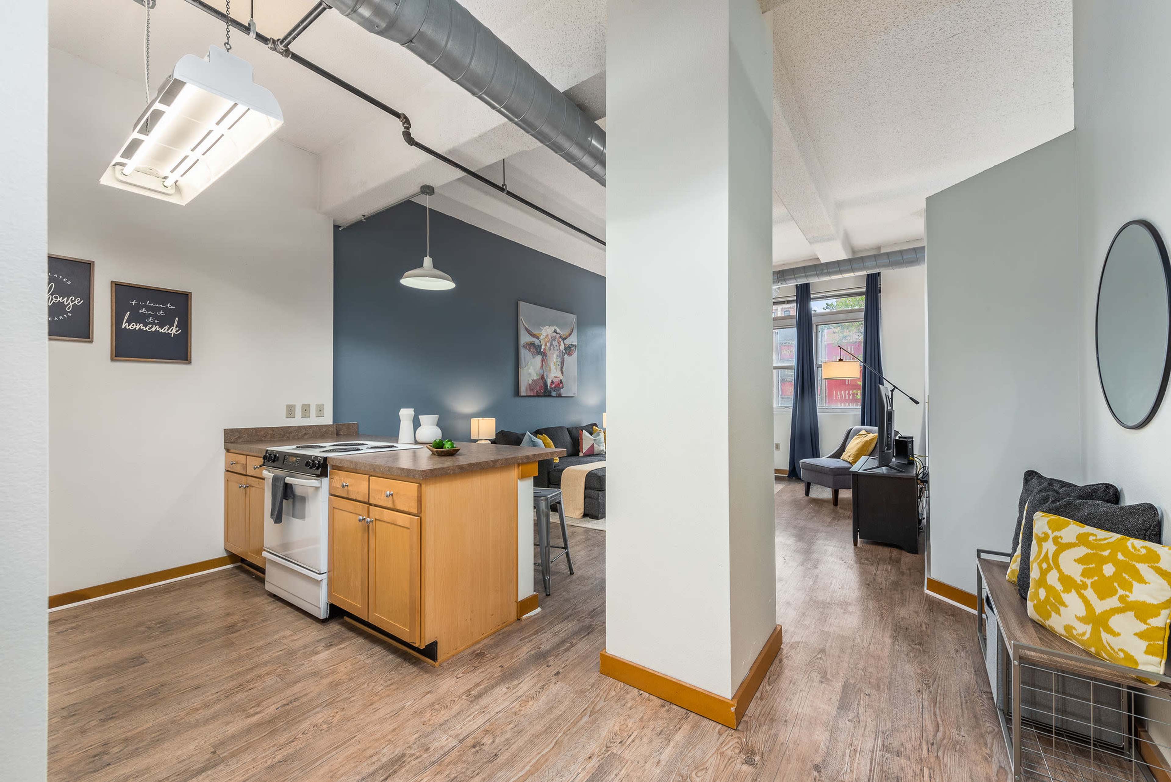 A modern open-concept apartment featuring a kitchen with an island, a living area with large windows, and a casual seating arrangement.