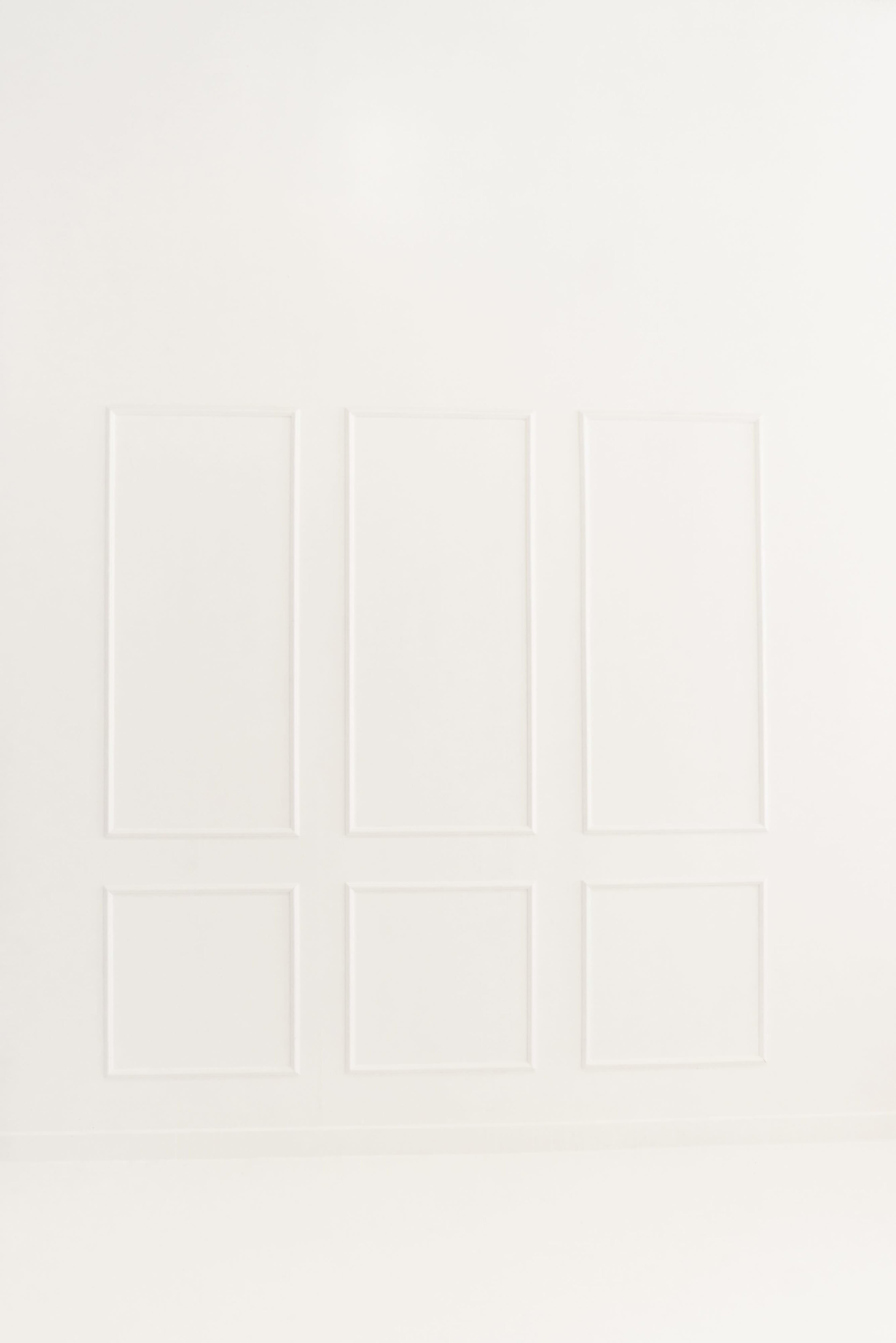 The image shows a plain white wall with three rectangular frames outlined in a subtle pattern.