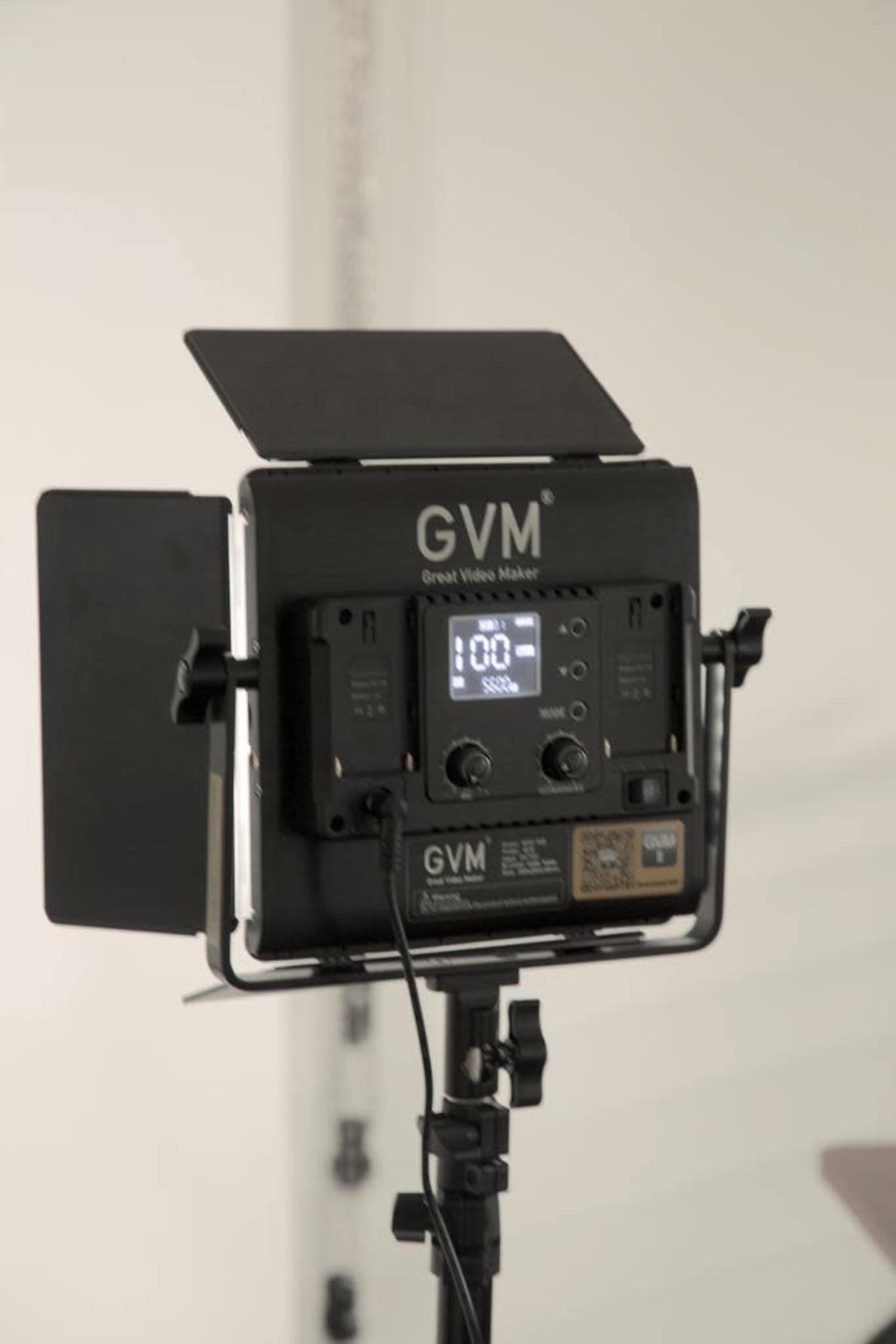 A GVM video light is set up on a stand with its control panel visible, displaying a digital screen.