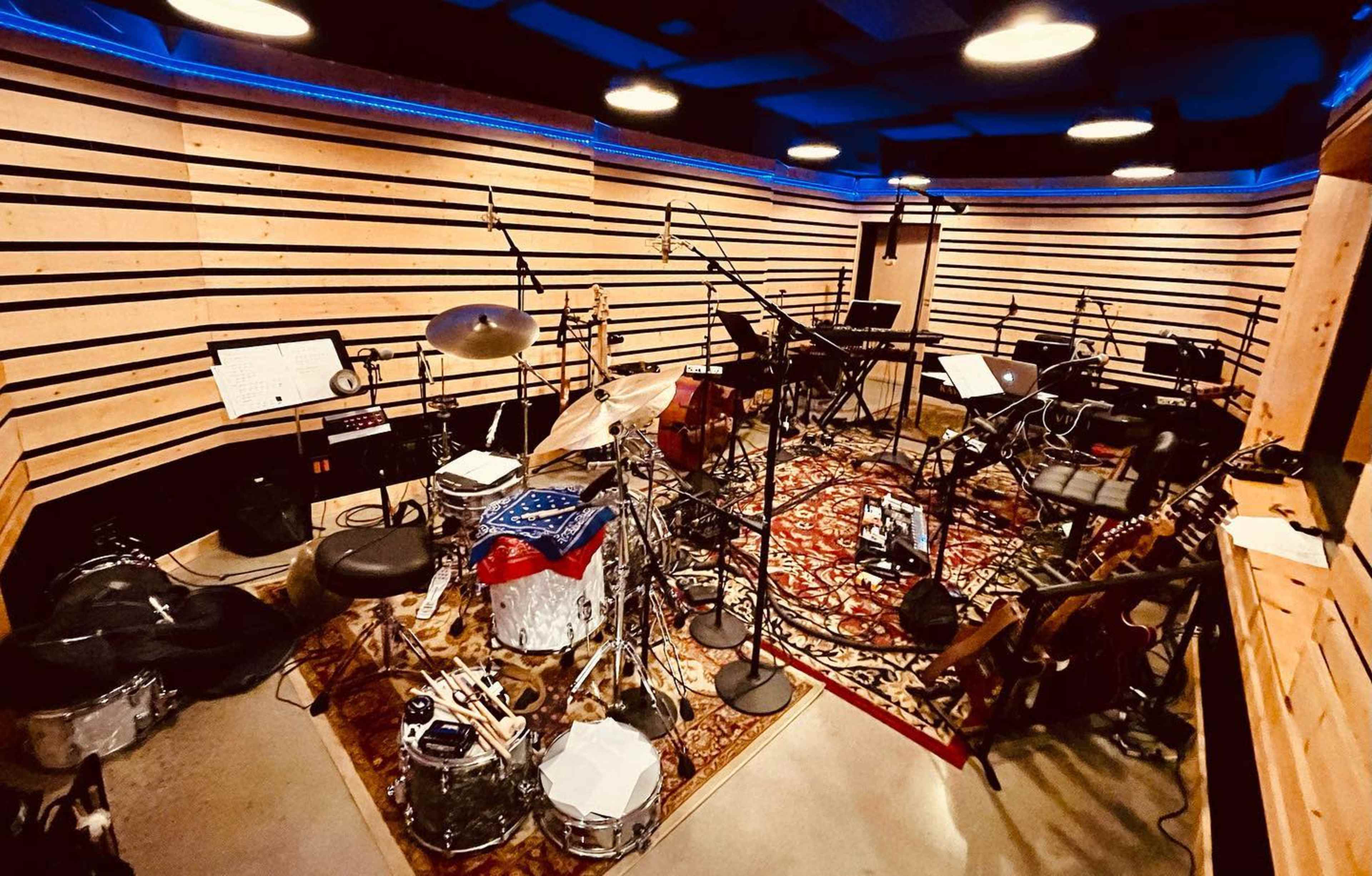 A music recording studio featuring various instruments, microphones, and sound equipment arranged on a patterned rug.