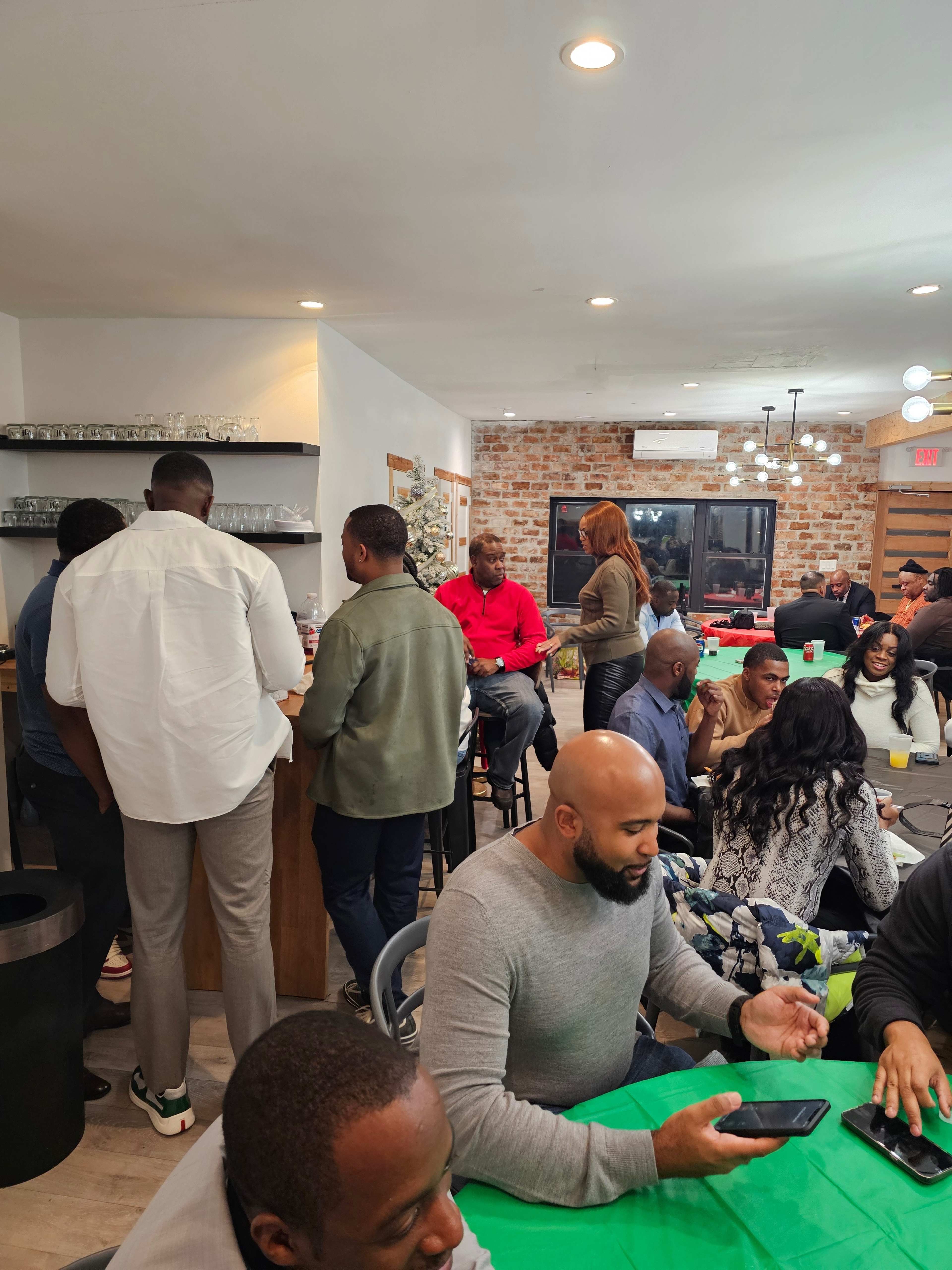 A group of people socializes inside a modern venue with brick walls and a bar area.