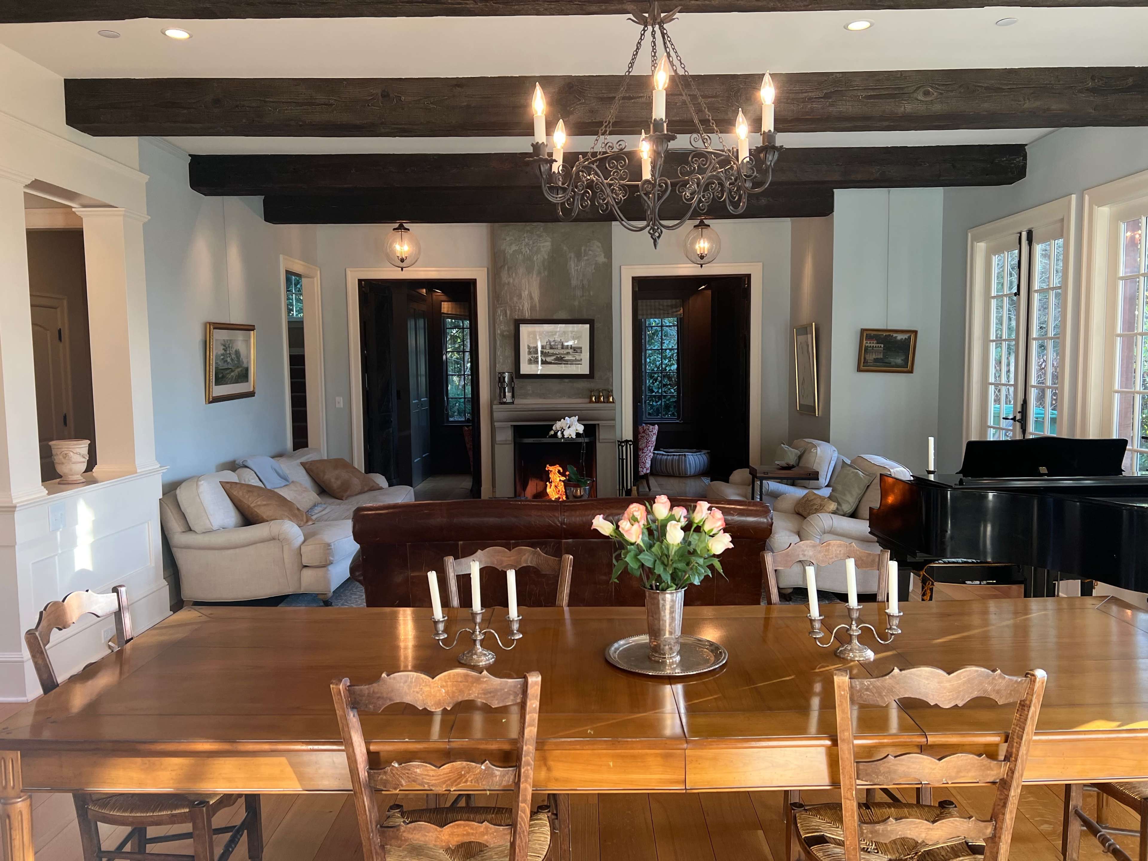 A spacious living area features a dining table with candles in the foreground, while a piano and comfortable seating are visible in the background.