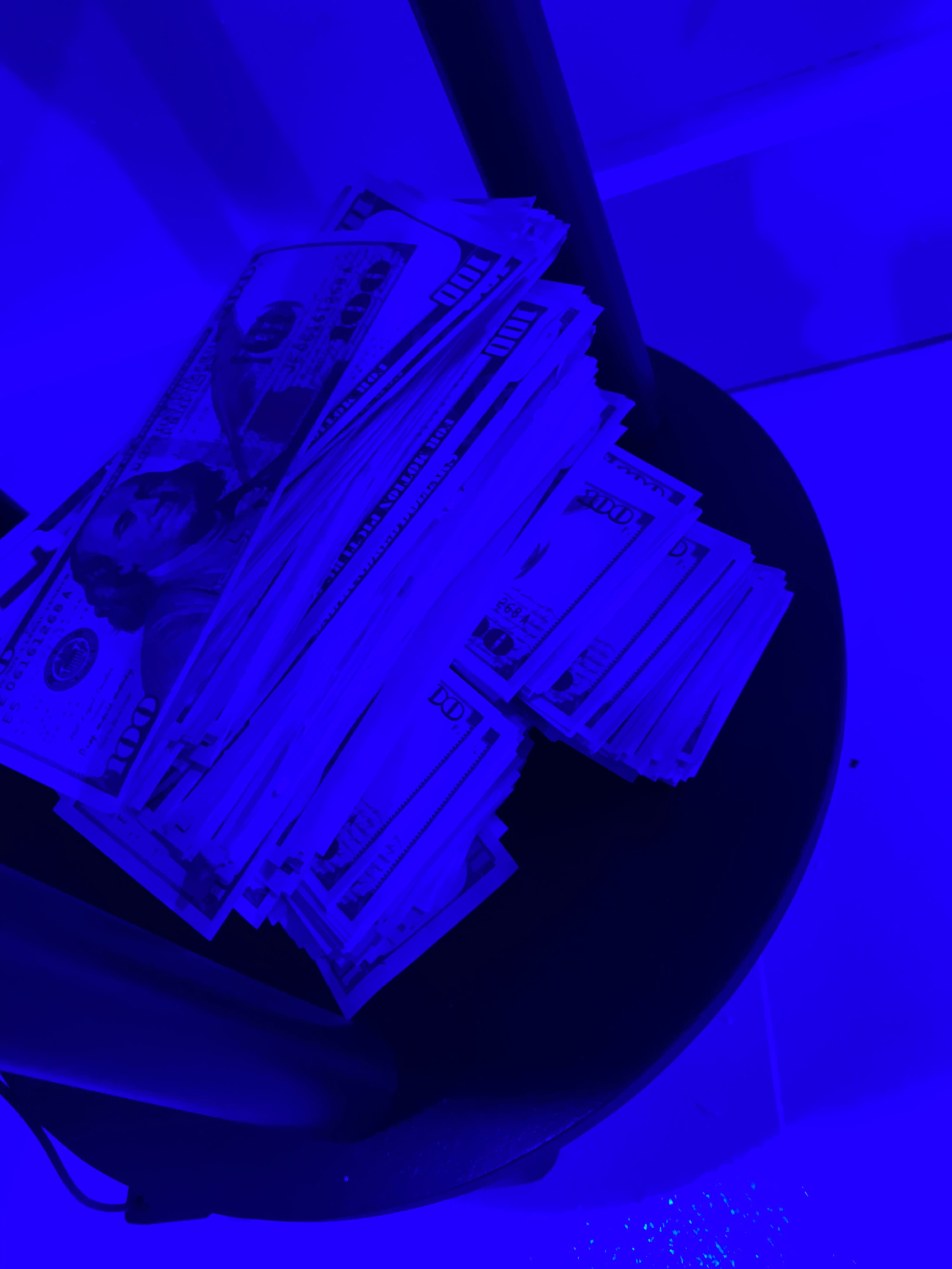 A stack of U.S. currency notes is placed on a round black stool.