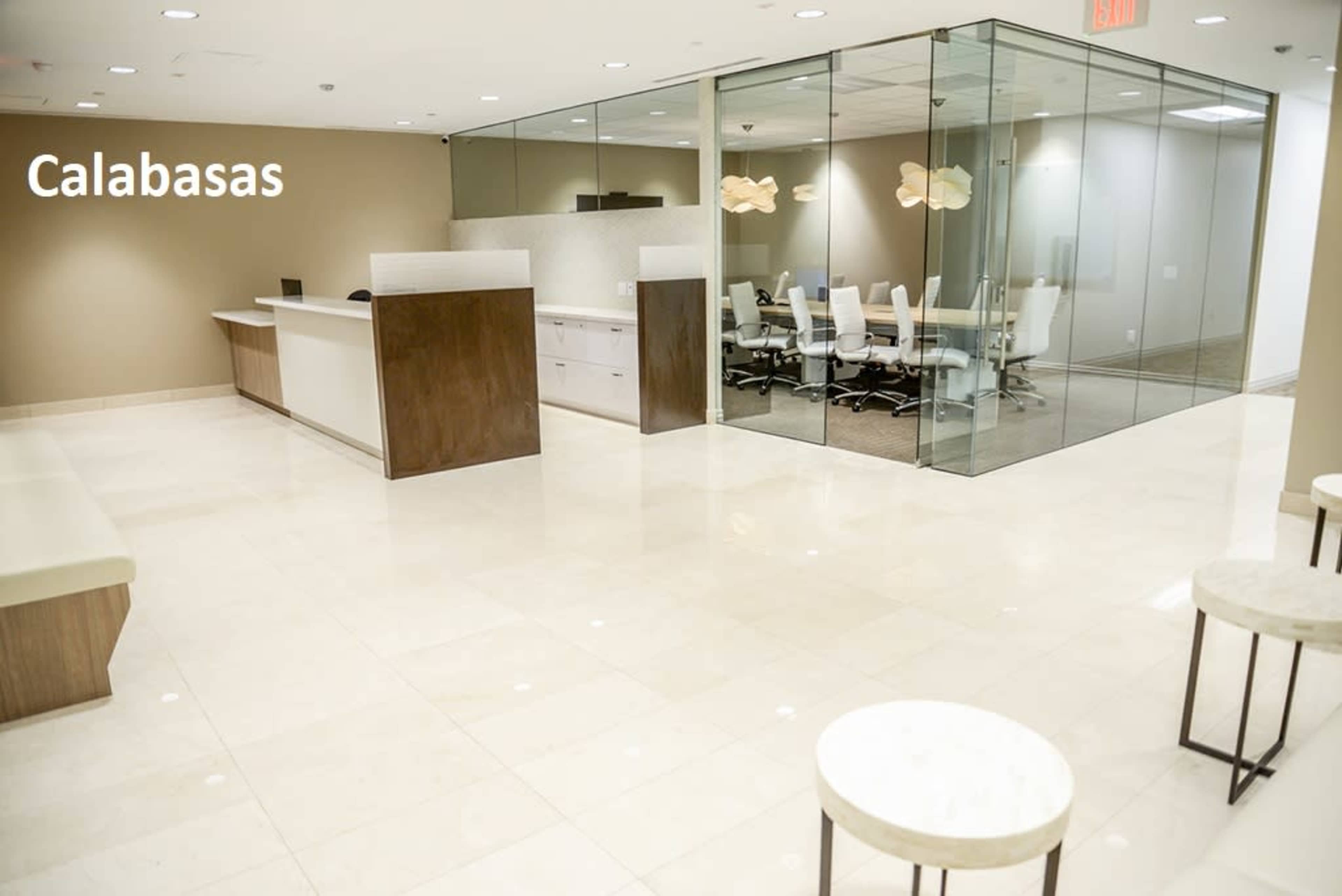 A modern office reception area with a front desk and a glass-enclosed conference room.
