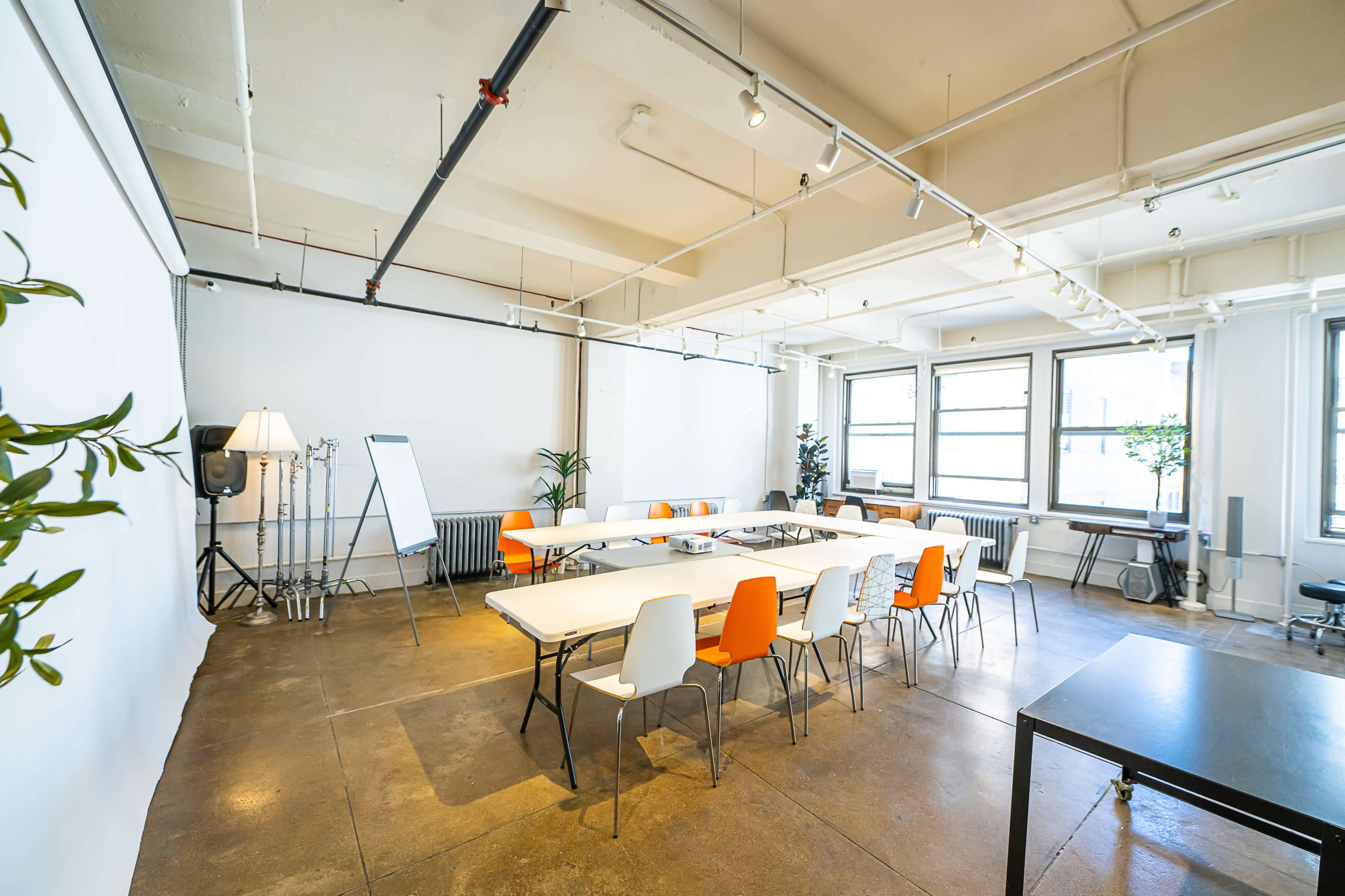 A spacious meeting room features a long table surrounded by chairs, with large windows and minimalistic decor.