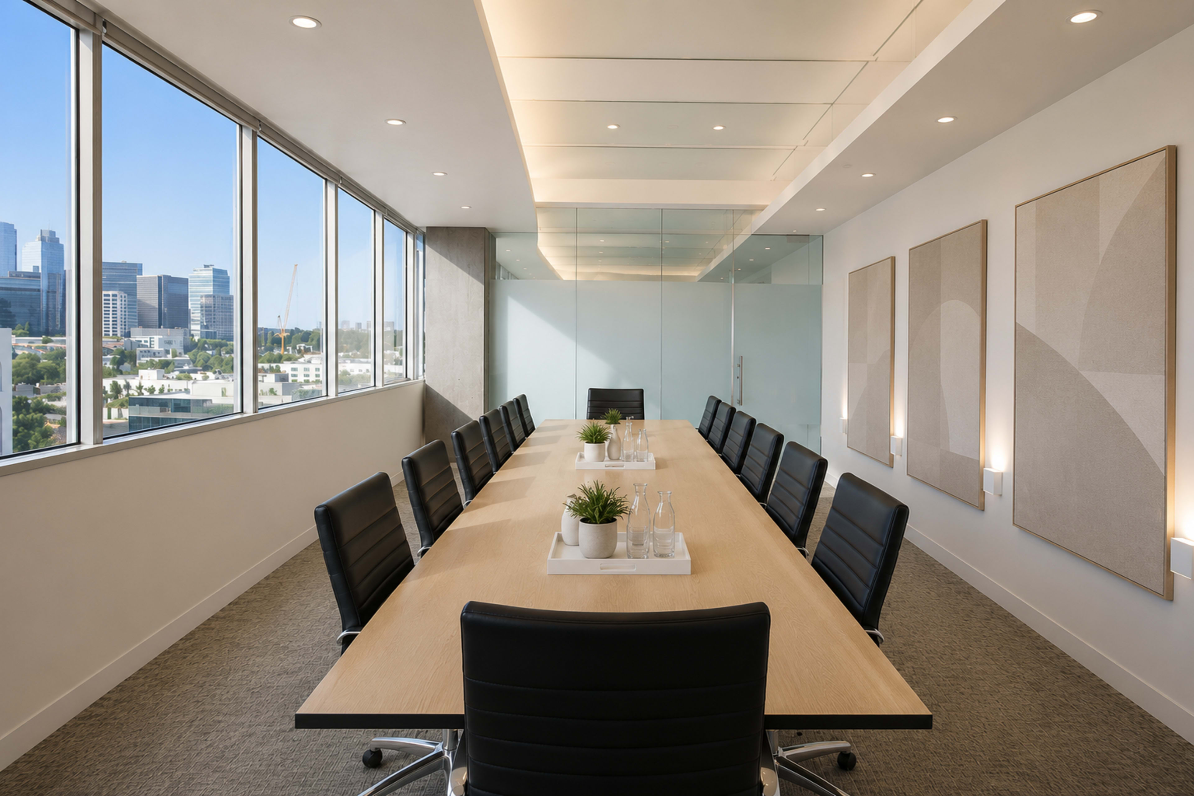A modern conference room features a long wooden table surrounded by black leather chairs and large windows that provide a view of the city skyline.