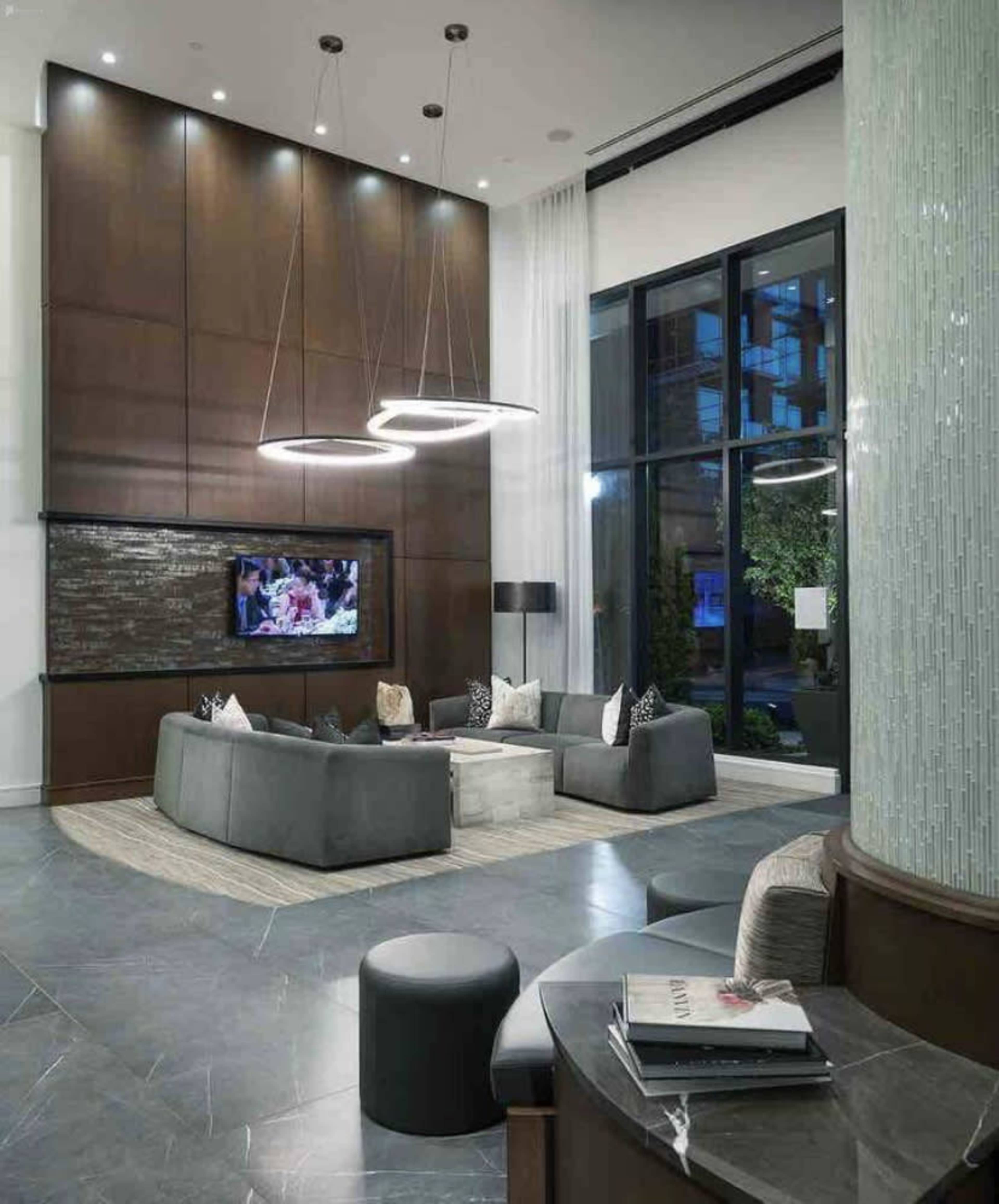 The image shows a modern lounge area with a large seating arrangement, a coffee table, and a television mounted on the wall.