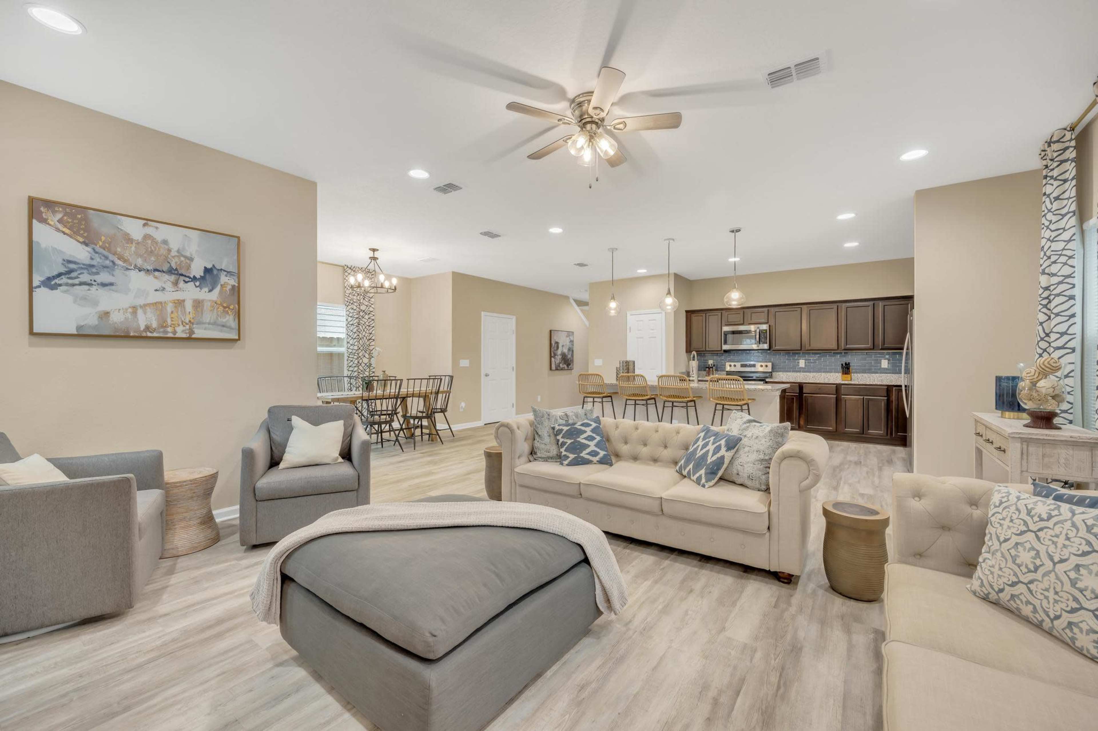 The image shows a modern living room with beige walls, a comfortable seating area, and an adjacent dining space visible in the background.