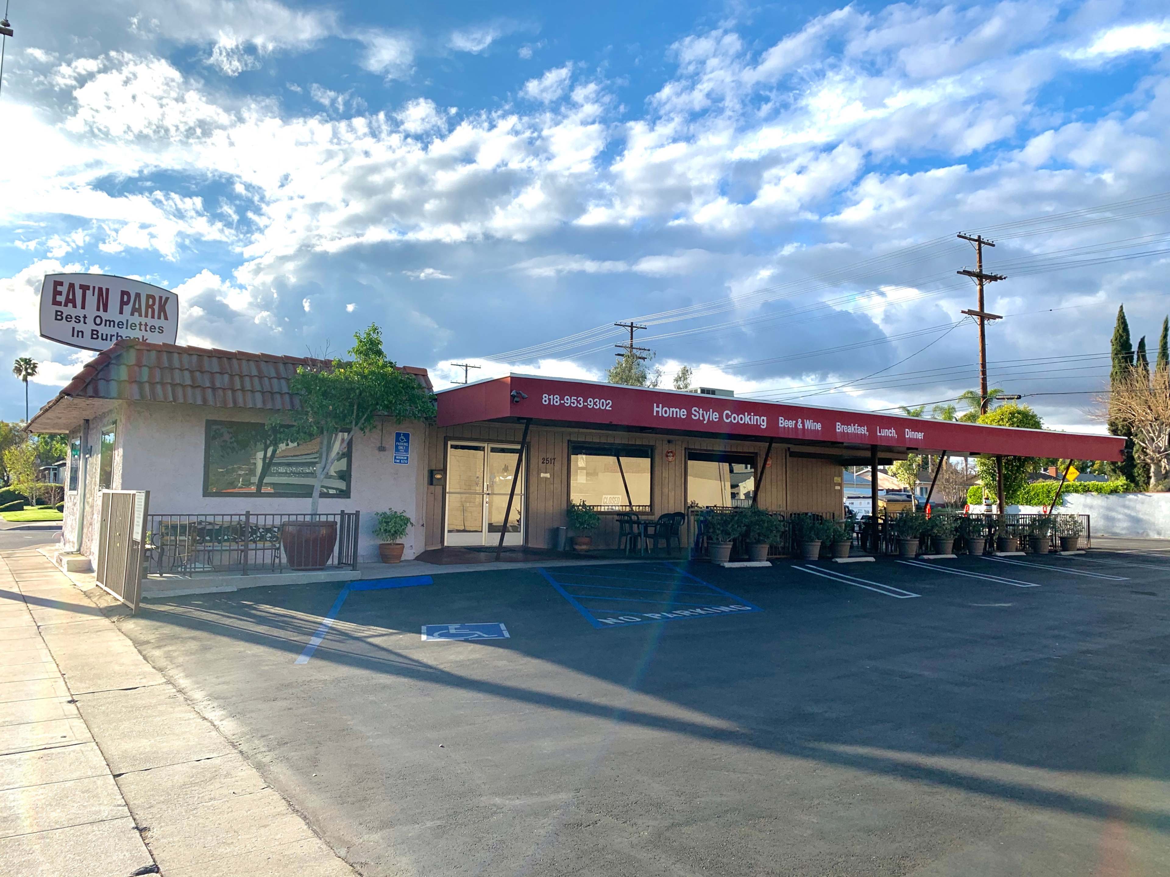 The image shows a single-story restaurant named "Eat n Park" with a red awning, surrounded by a parking lot and featuring a clear sky in the background.