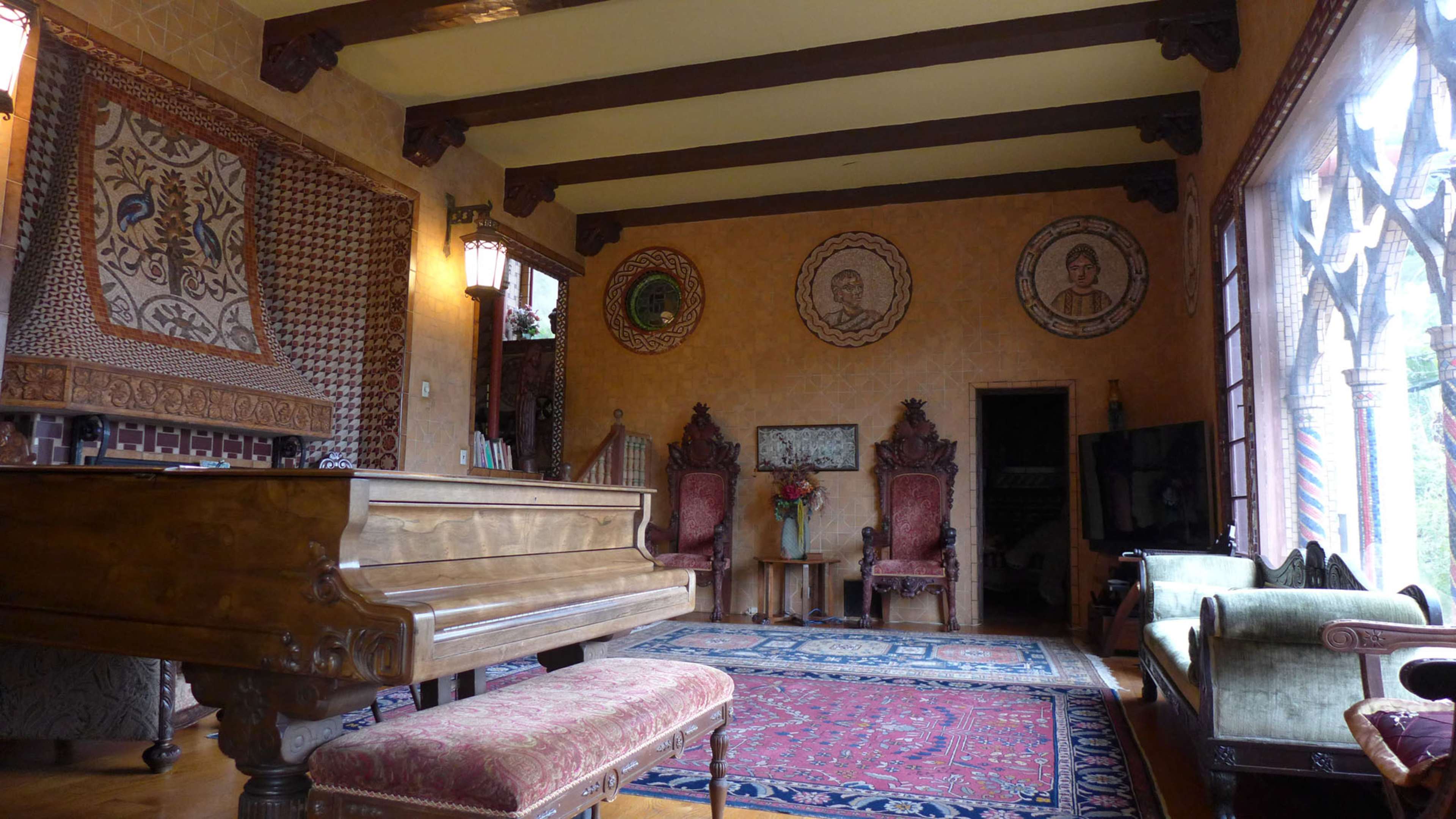 The interior of a room features a grand piano, antique furniture, and ornate wall decorations, including portraits and textile patterns.