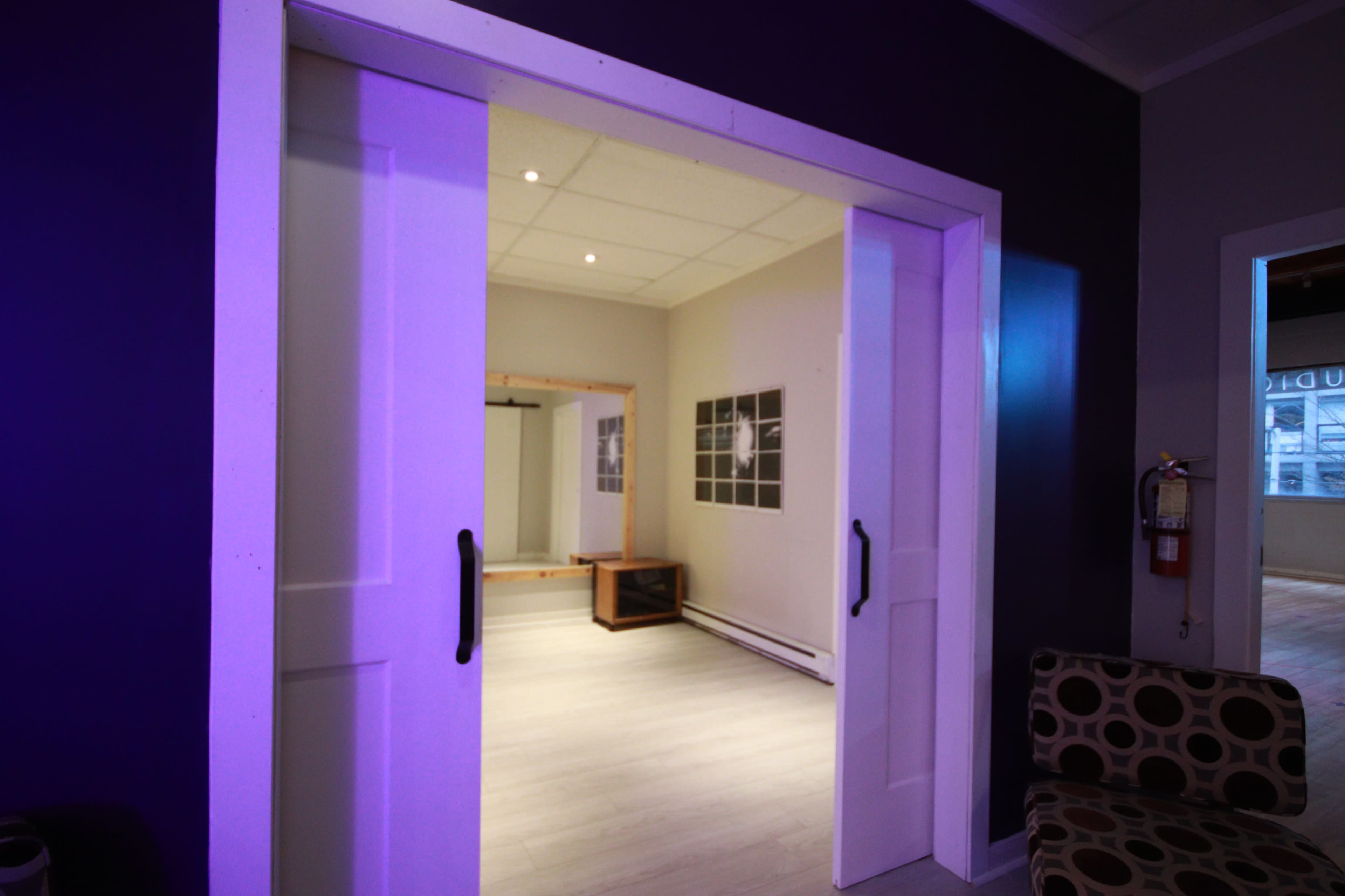 The image shows a partially open sliding door leading into a brightly lit room with minimalist decor and light-colored flooring.