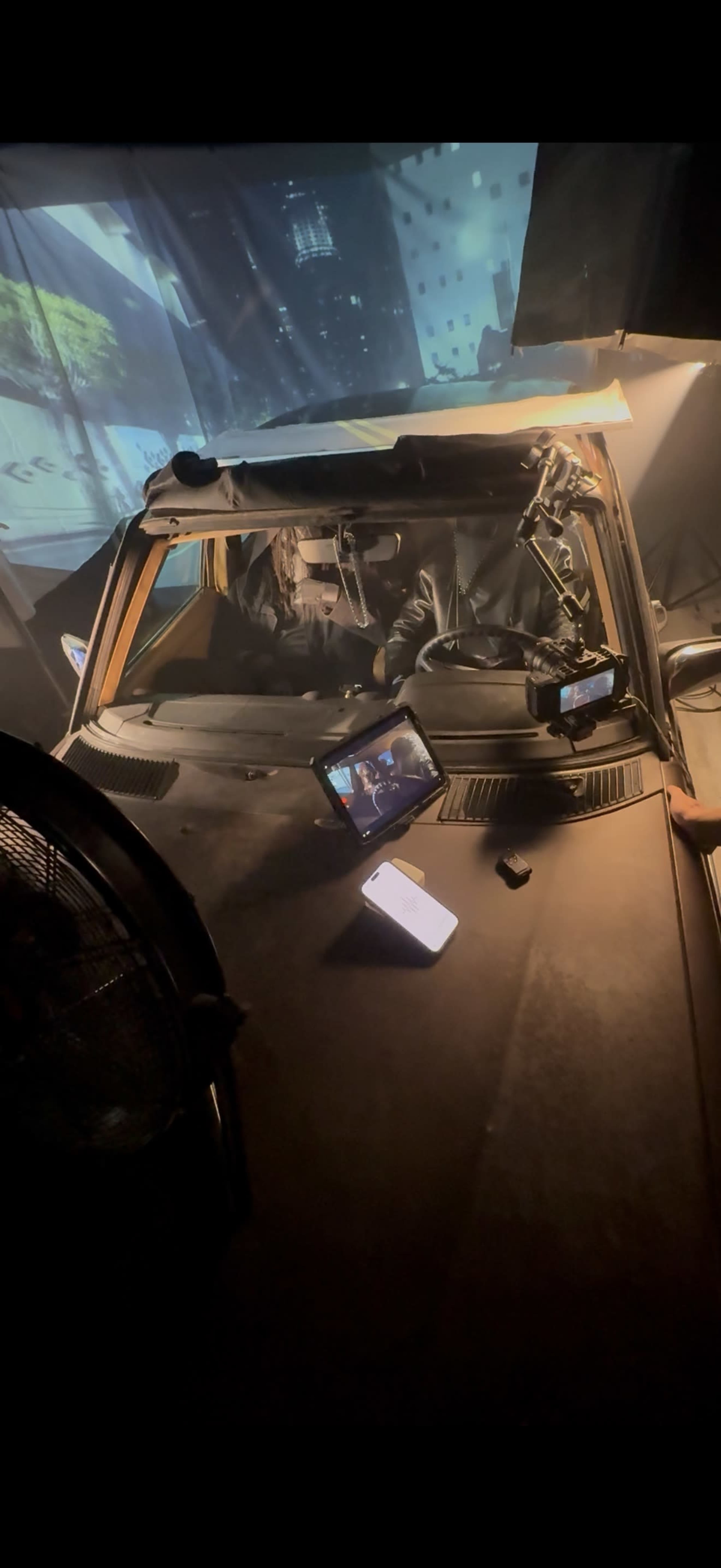 The image shows the interior of a car with a projection on the windshield and various electronic devices placed on the dashboard.