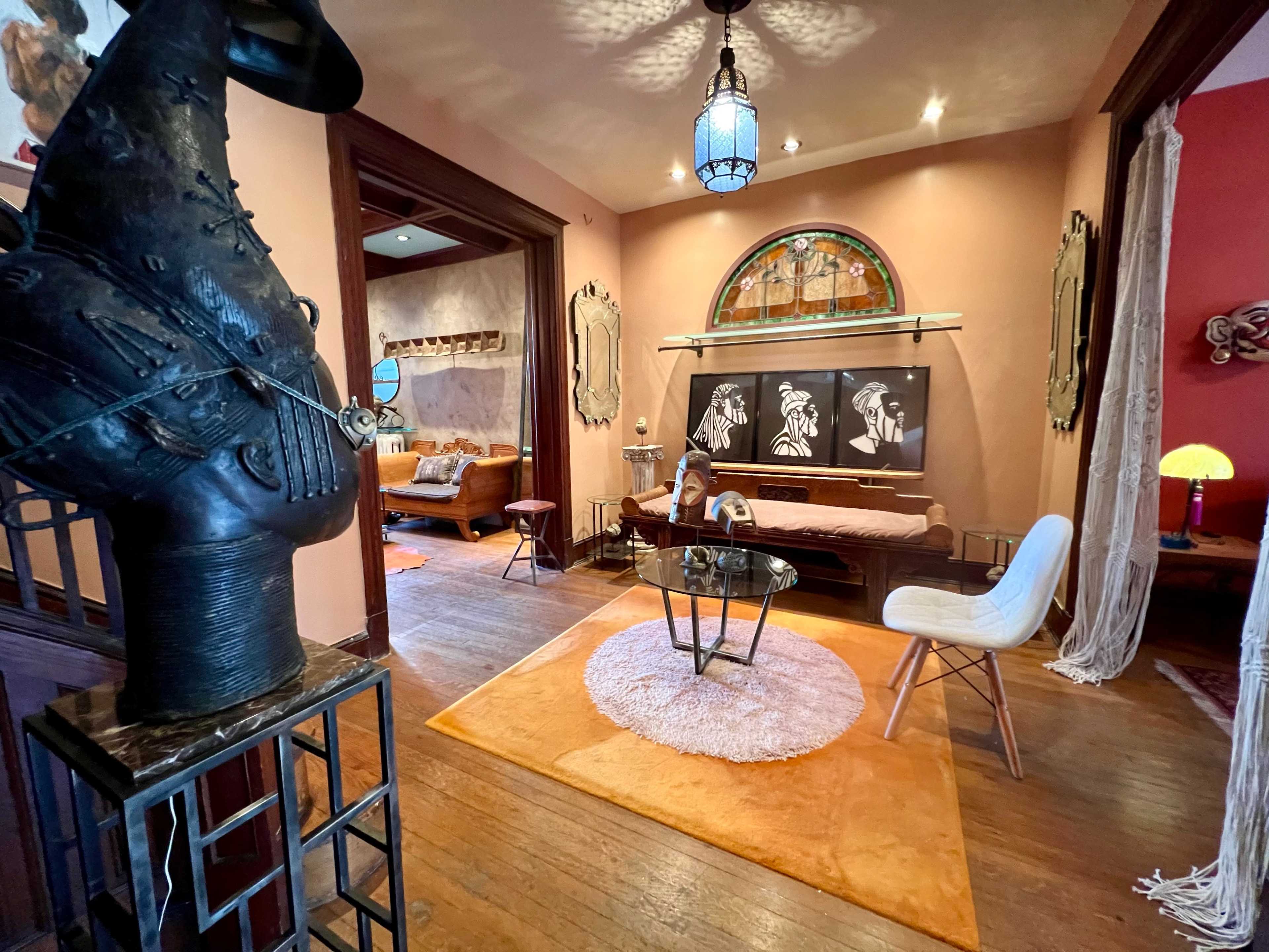 A stylish interior with a large stained glass window, a coffee table, and various artworks displayed on the walls.