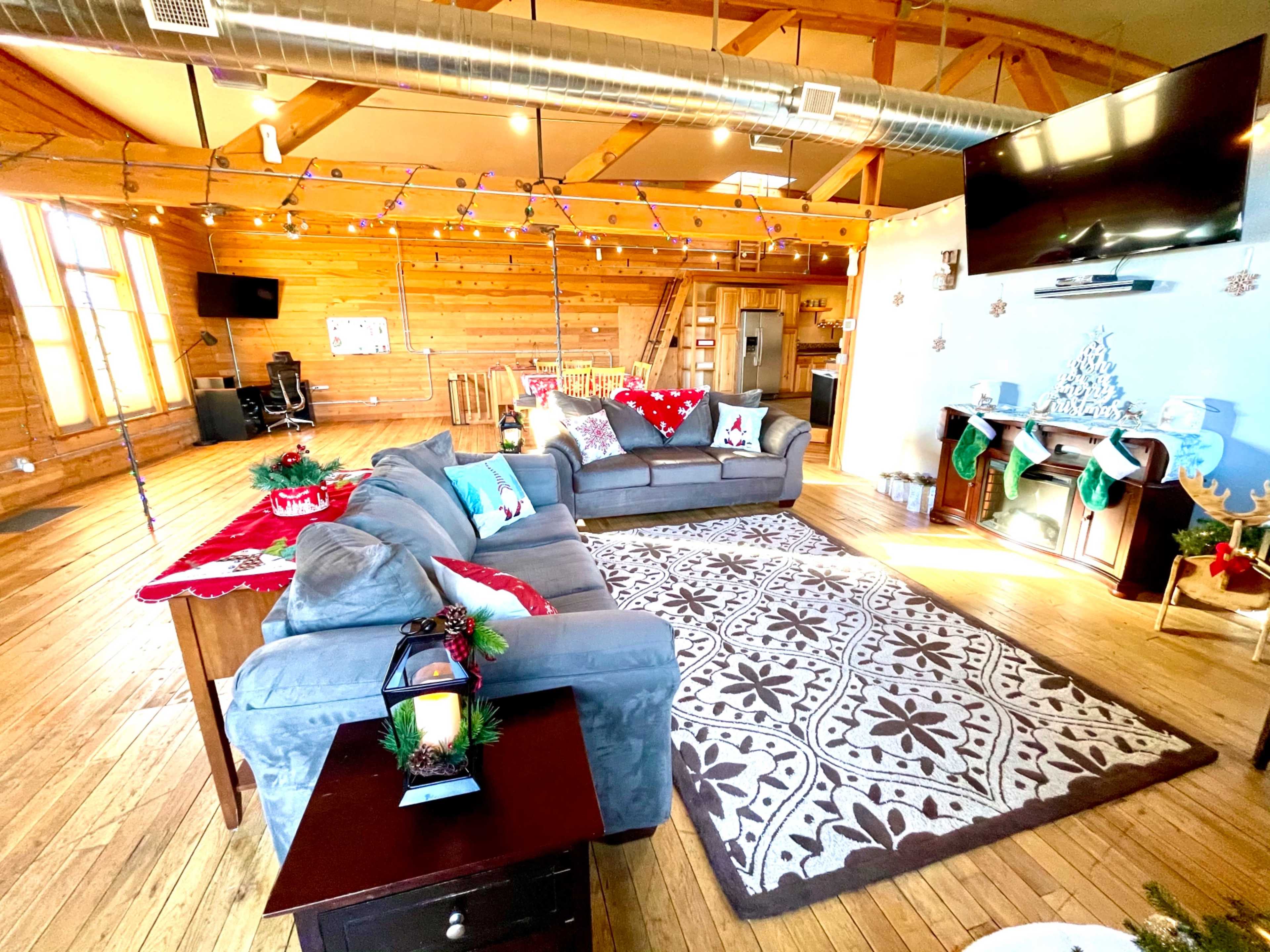 The living room features two sofas arranged around a coffee table, a large area rug, and decorations for a festive atmosphere.