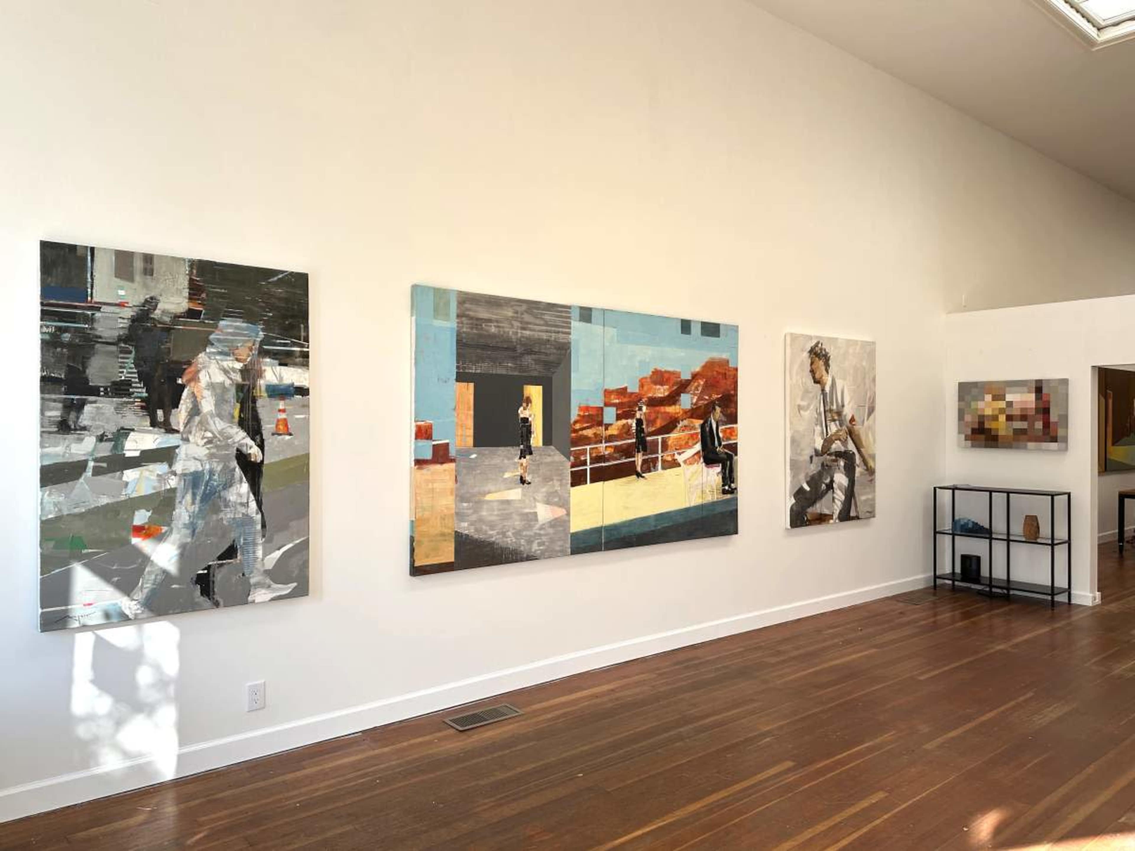 The image shows a gallery wall featuring four abstract paintings and a small display case with various objects.