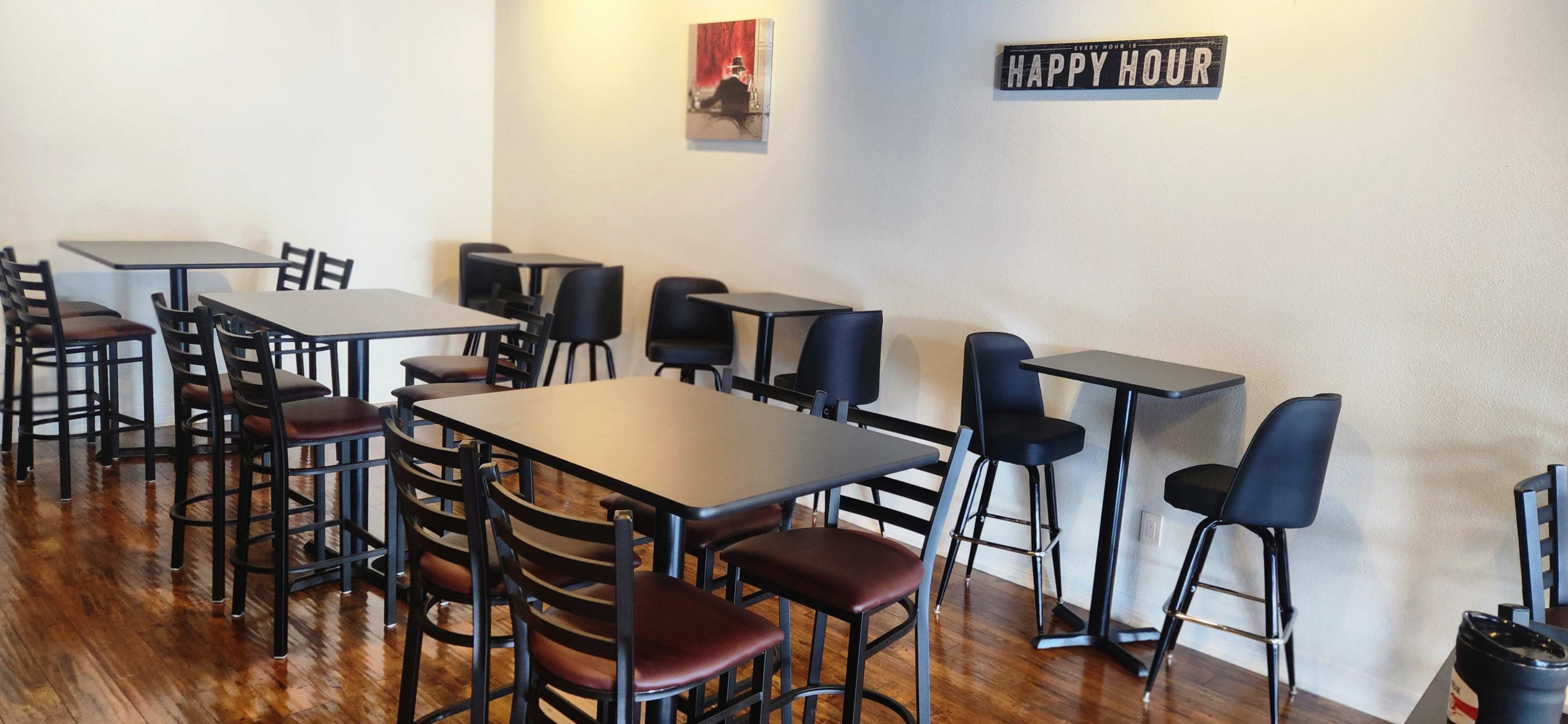 The image shows a spacious, minimally decorated café with empty tables and chairs arranged neatly against the walls.