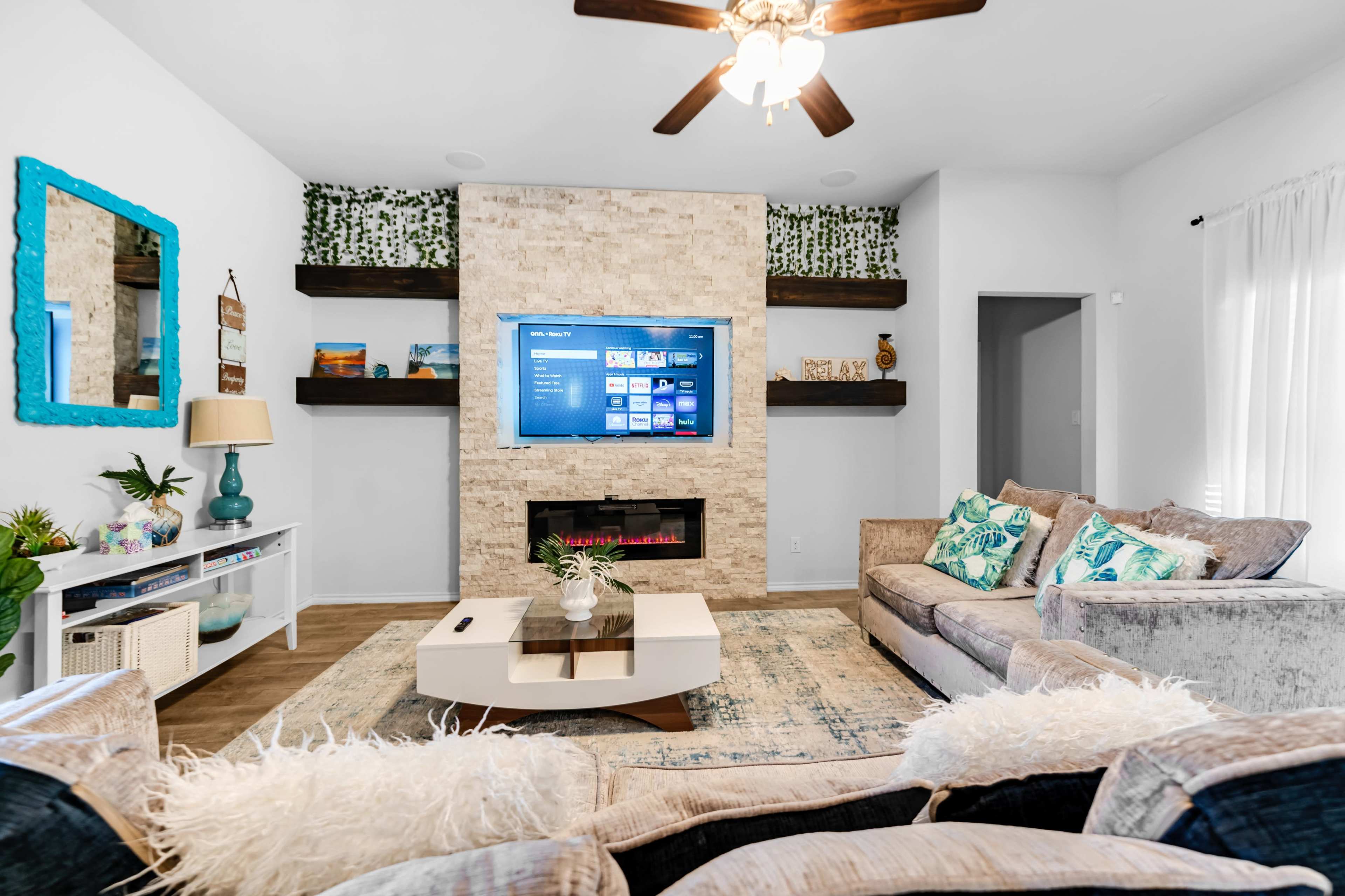 A modern living room with a stone accent wall, a mounted television, and two sofas with decorative pillows around a coffee table.