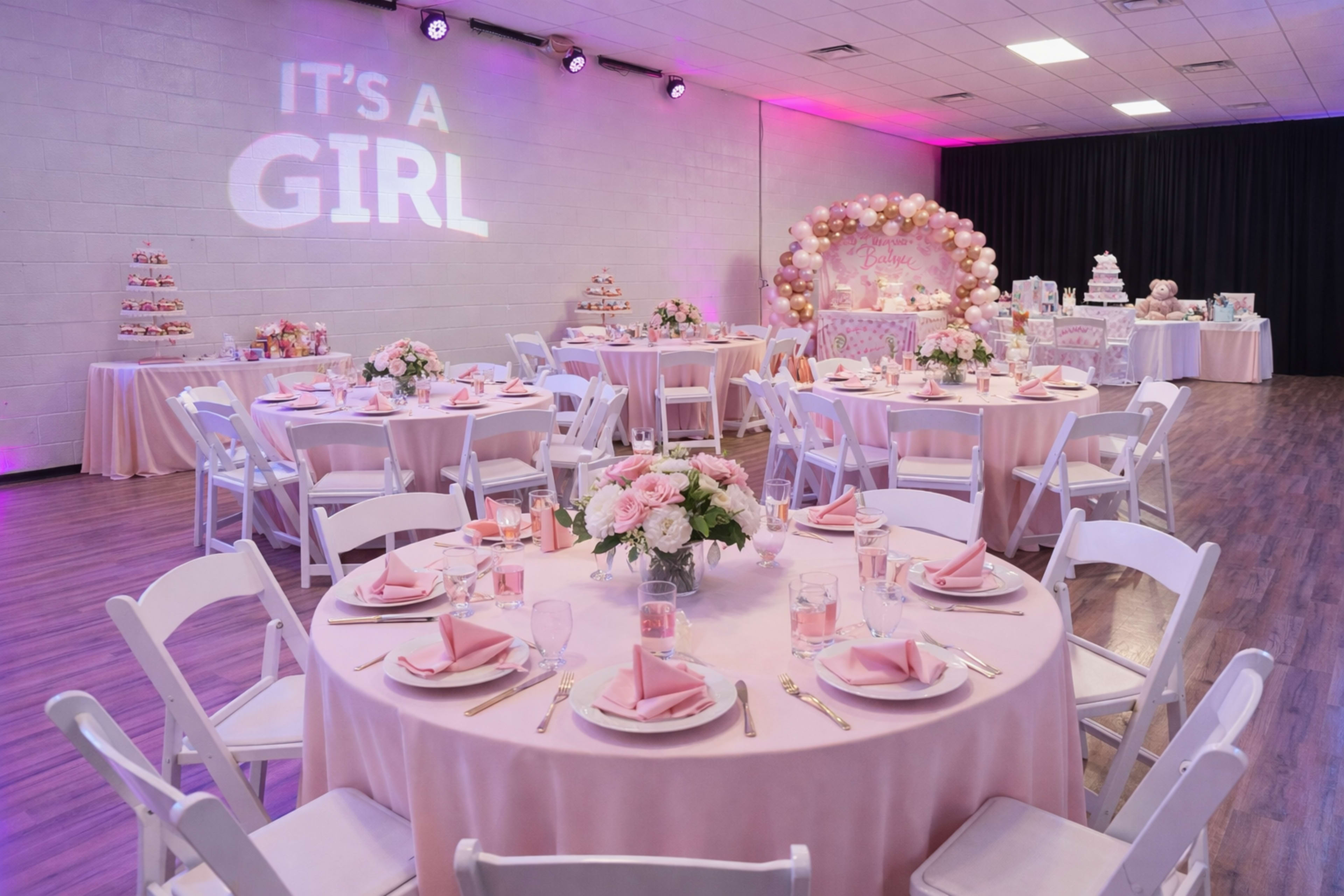 The image depicts a decorated event space celebrating a baby shower, featuring pink table settings, floral centerpieces, and a cake display.