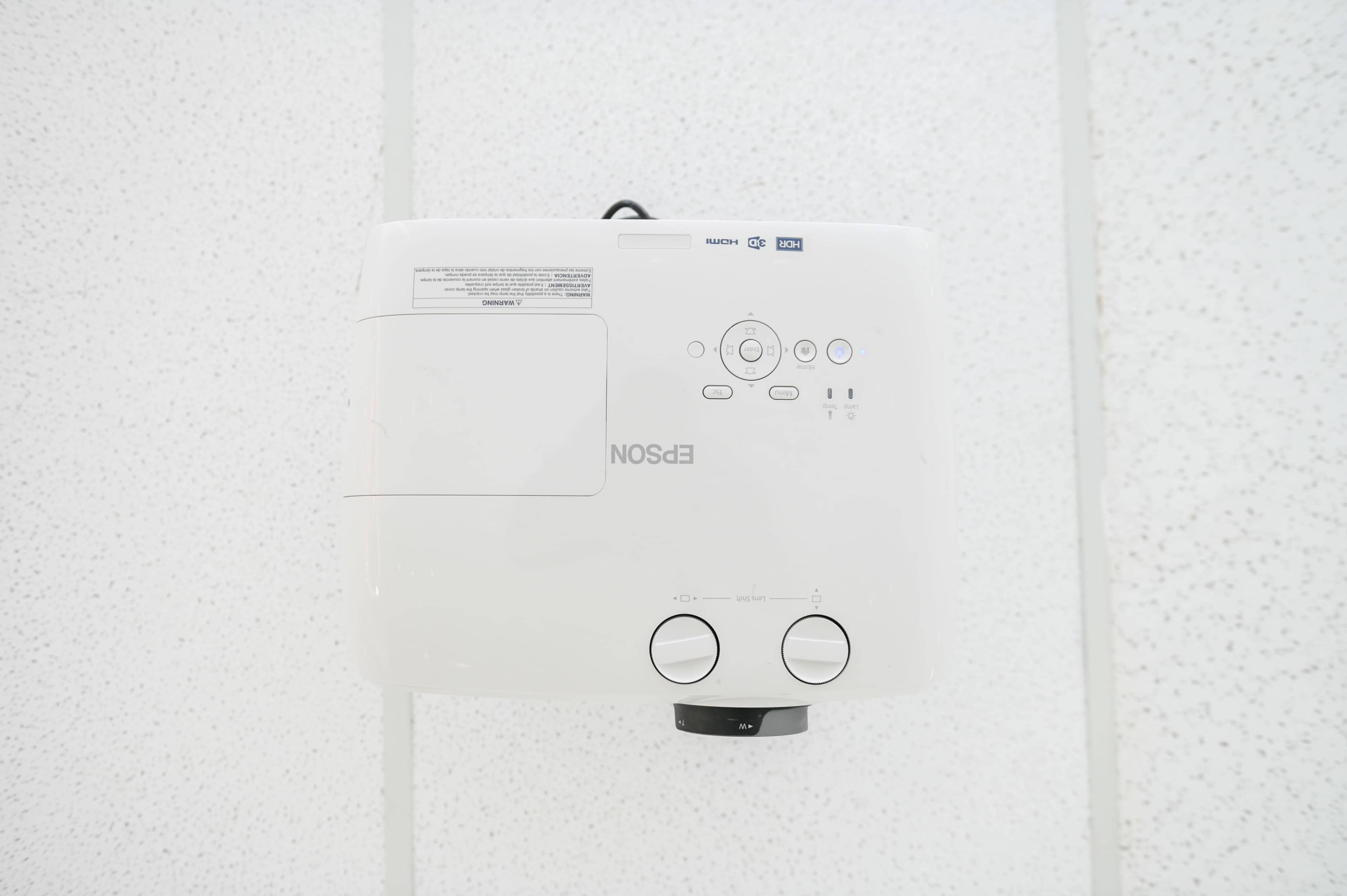 A white Epson projector is positioned on a textured light-colored surface.