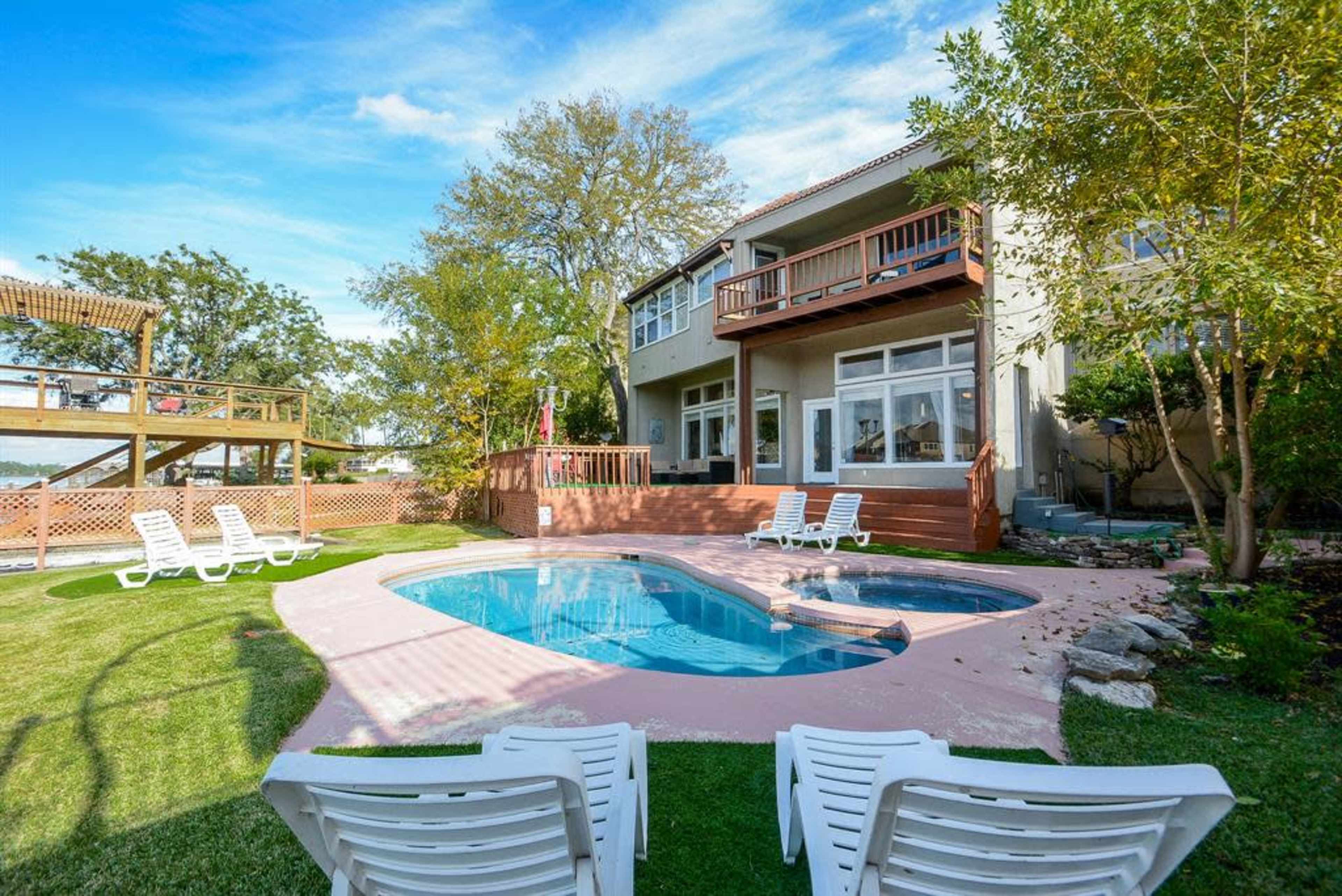 A backyard with a swimming pool, lounge chairs, and a house with multiple balconies.