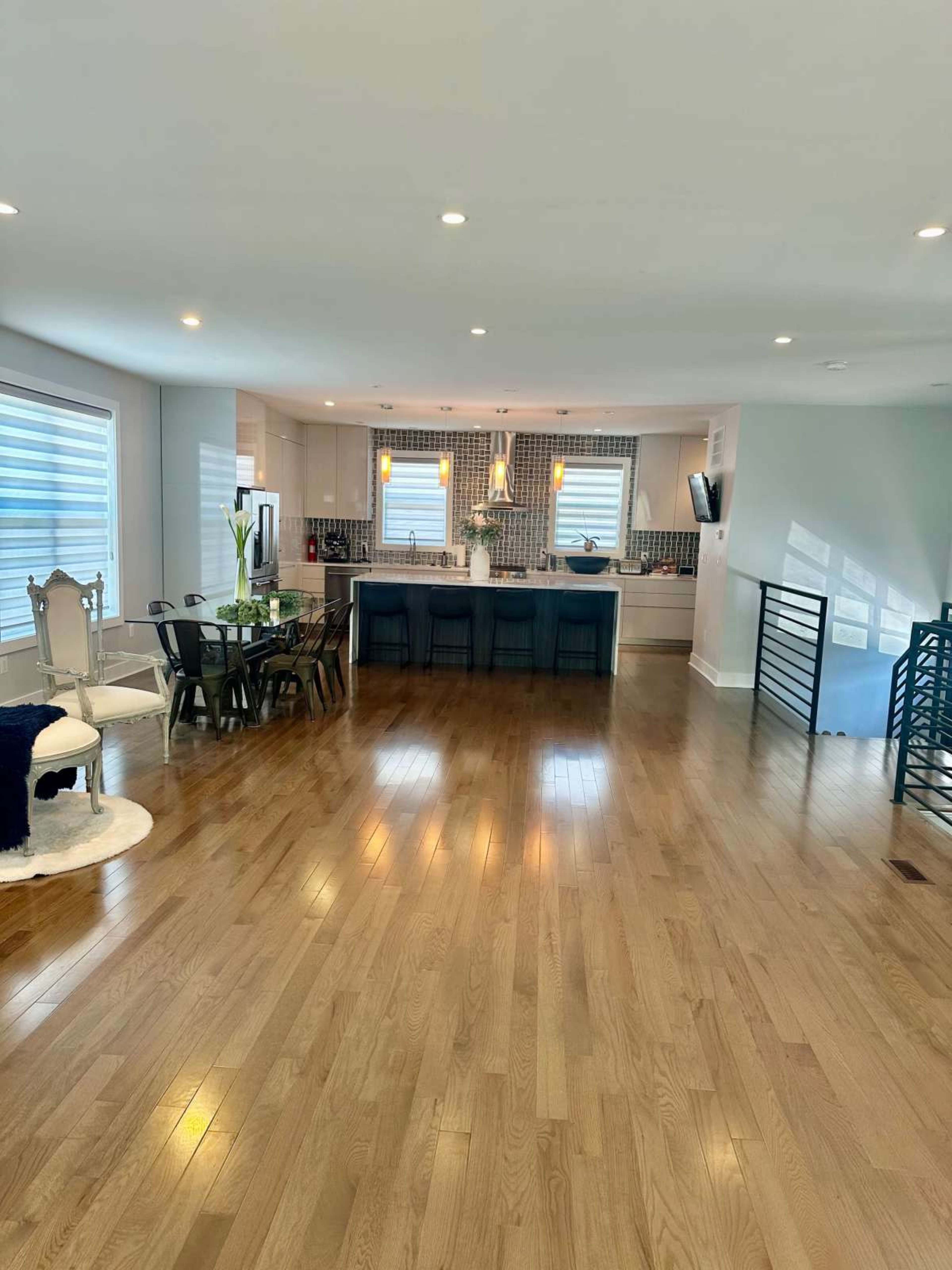 A spacious open-concept living area featuring a dining table, modern kitchen, and hardwood floors.
