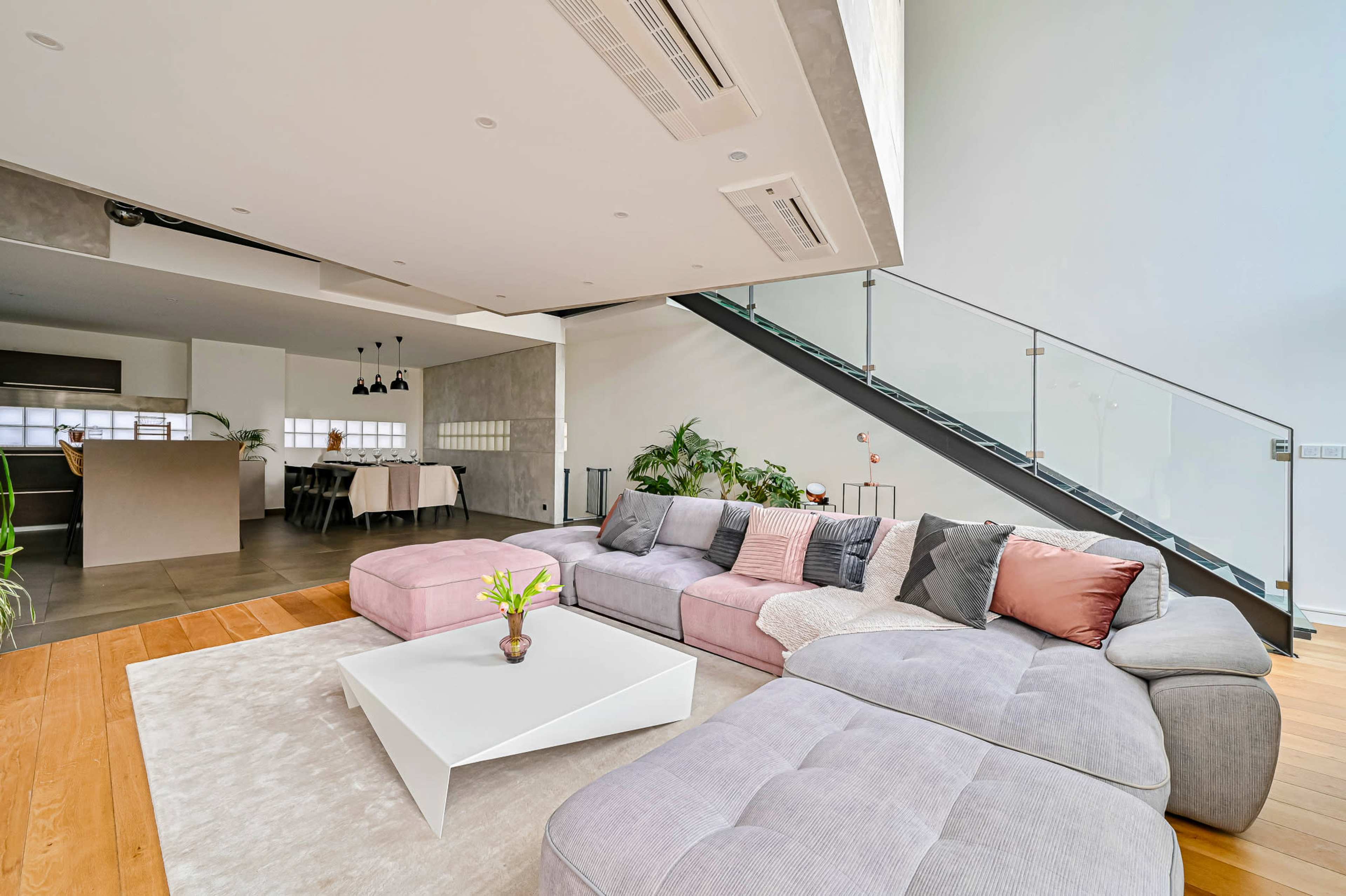 A modern living room with a large sectional sofa, a coffee table, and a staircase leading to an upper level.