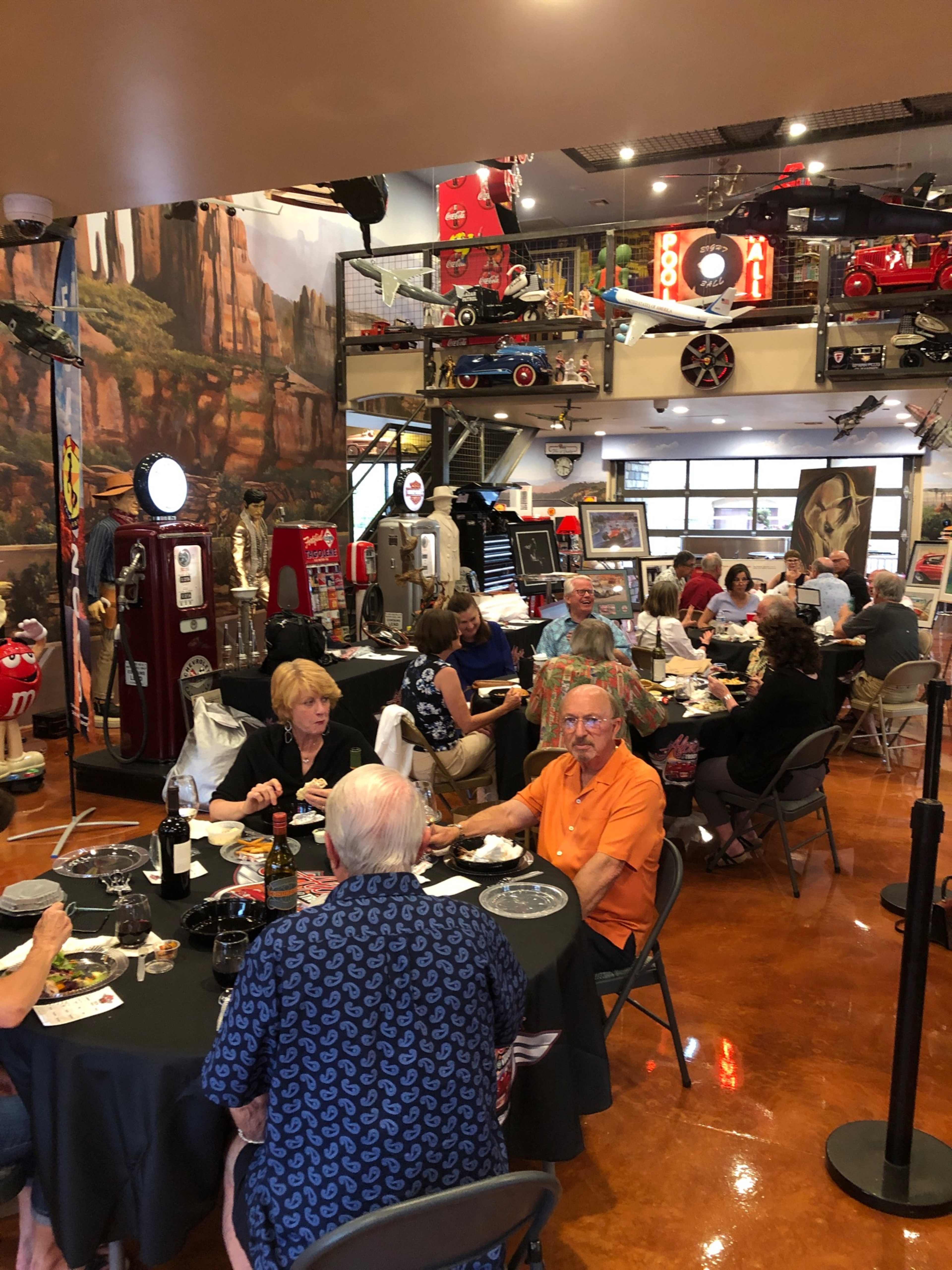 A group of people are sitting at tables in a restaurant surrounded by vintage memorabilia and decor.