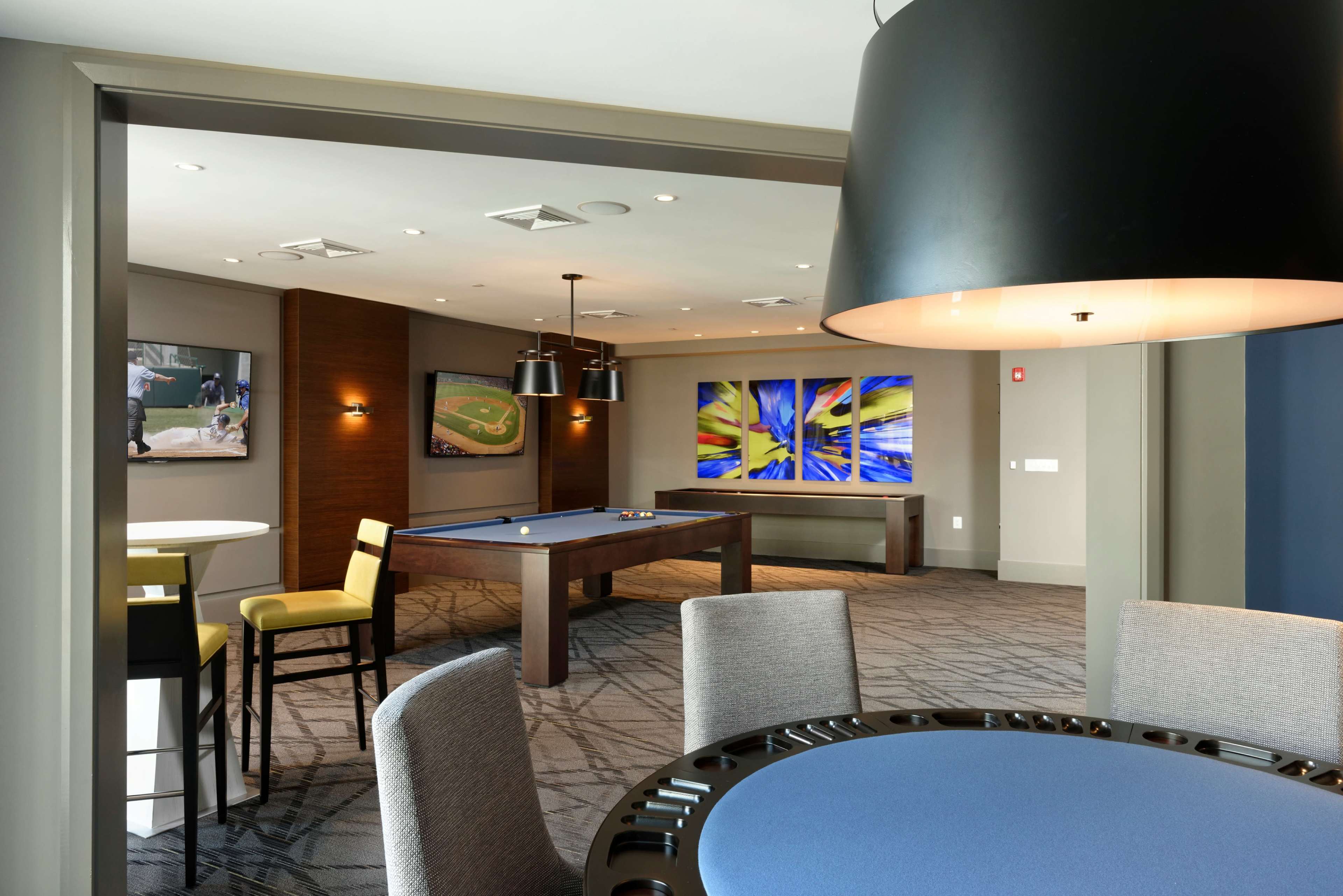 The image features a modern recreational room with a billiard table, contemporary artwork on the walls, and comfortable seating arrangements.