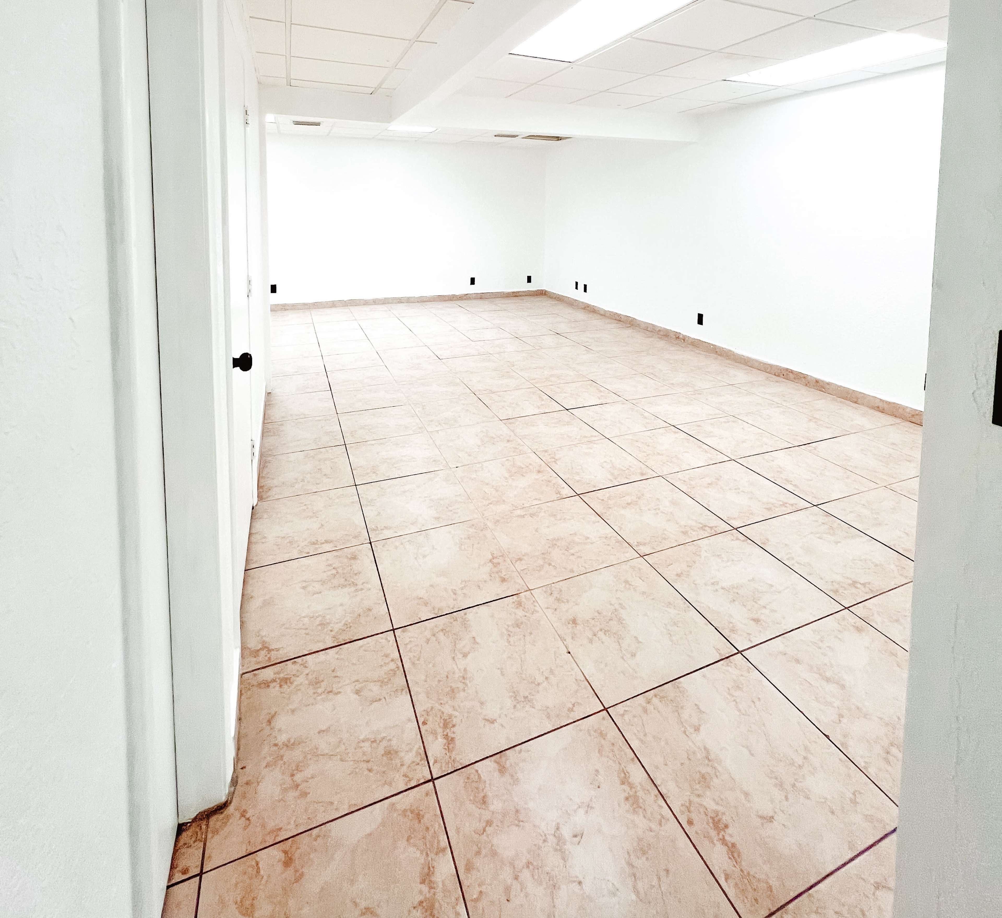 The image shows an empty room with light-colored tiled flooring and white walls.