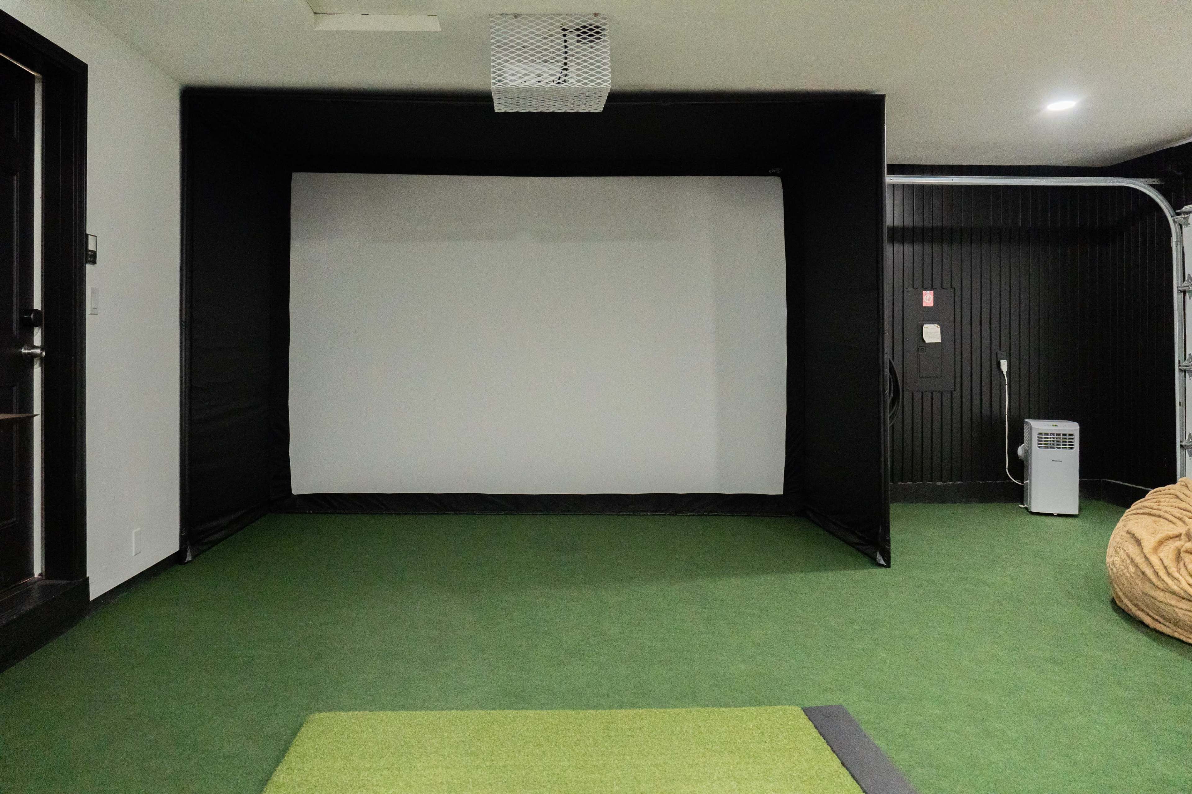 A large projection screen set up in a room with green carpet and minimal furnishings.