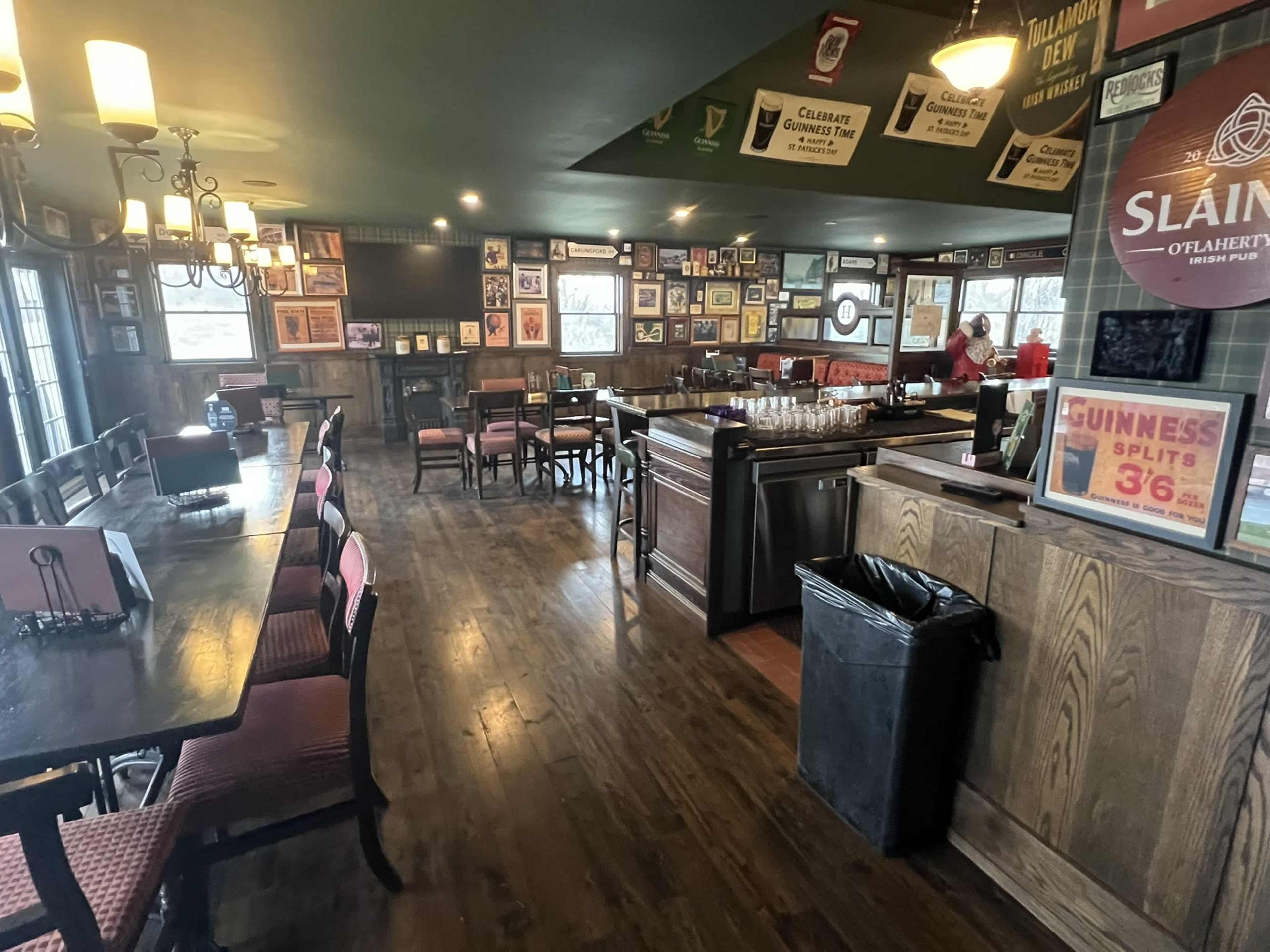 The interior of a pub features wooden floors, framed photographs on the walls, and tables with chairs arranged throughout the space.
