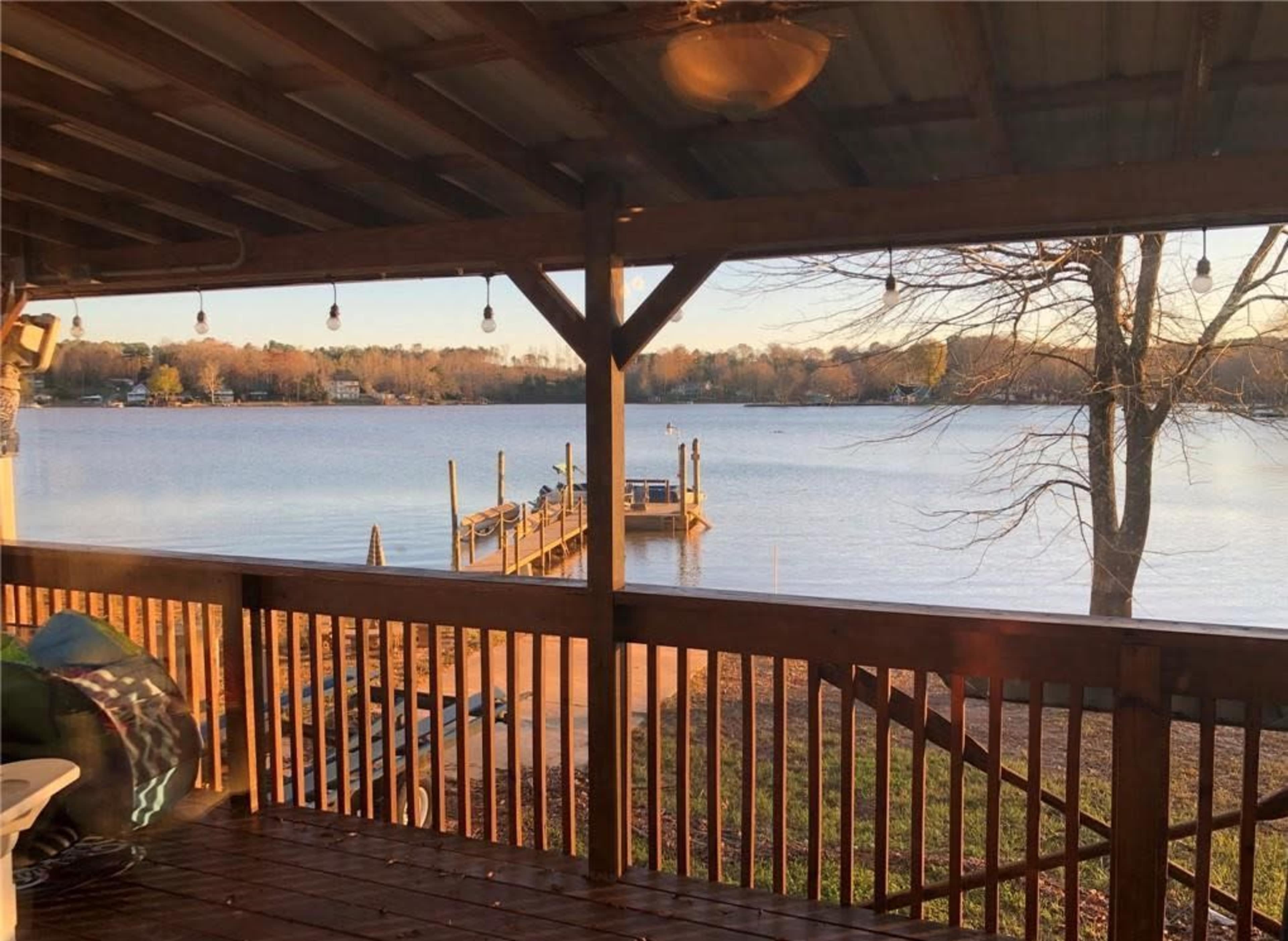 A wooden deck overlooking a tranquil lake with a dock extending into the water.