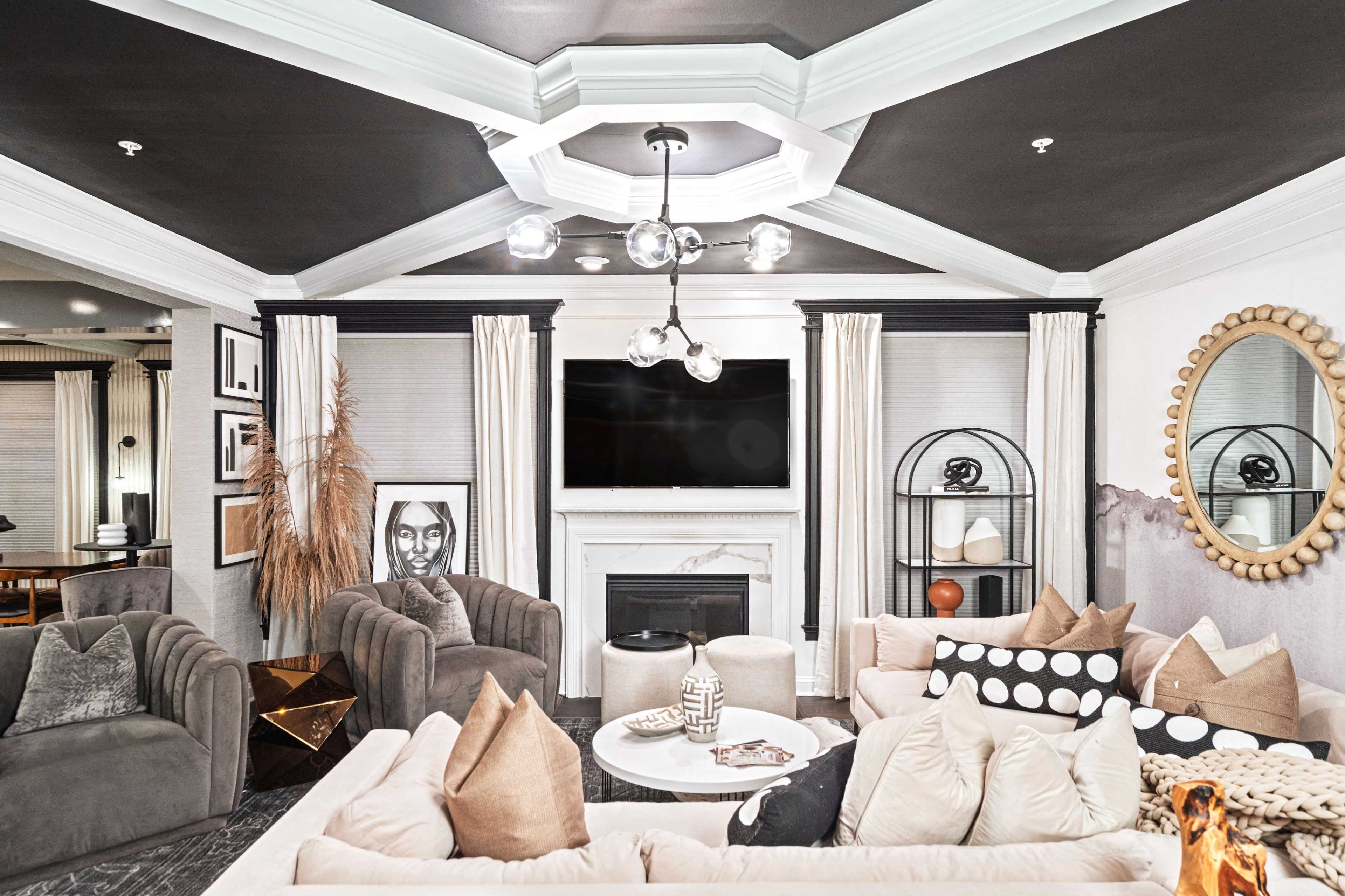 A modern living room features a central seating area with multiple sofas, a coffee table, and an elegant fireplace, framed by decorative lighting and wall art.