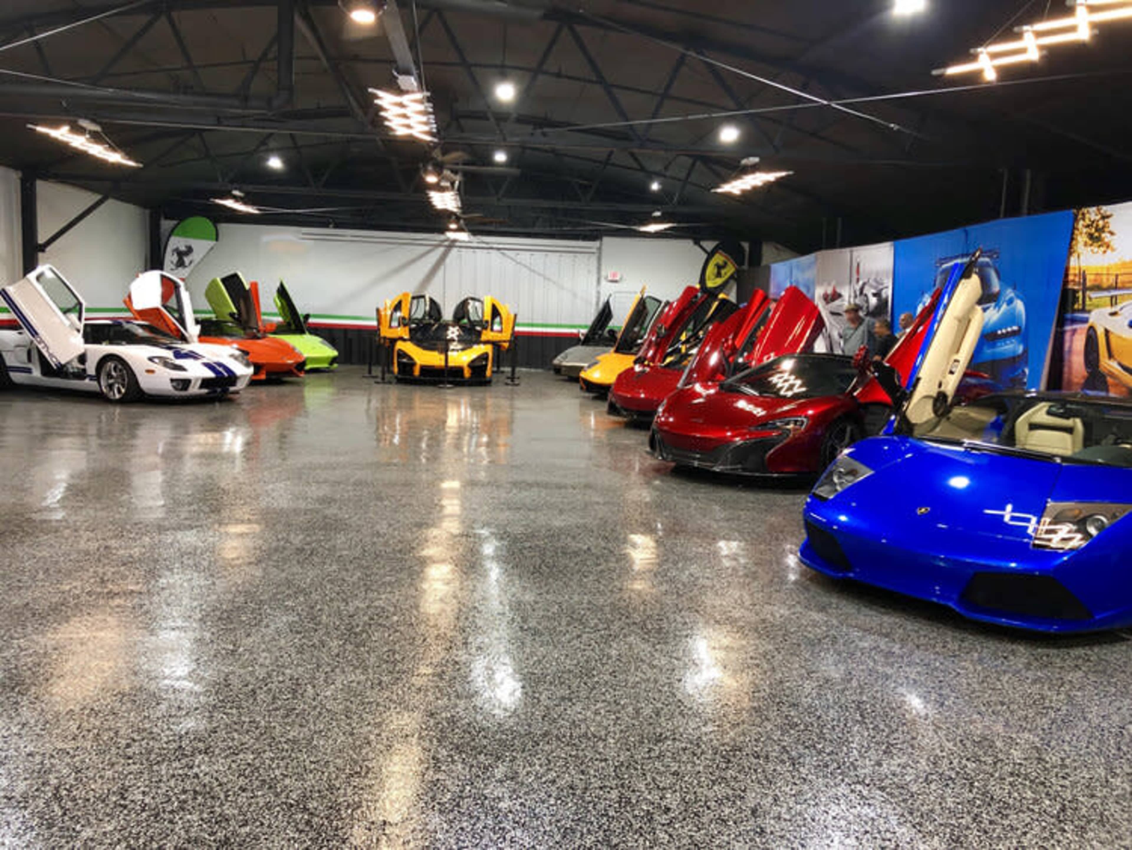A collection of luxury sports cars with their doors open, arranged in a well-lit garage.