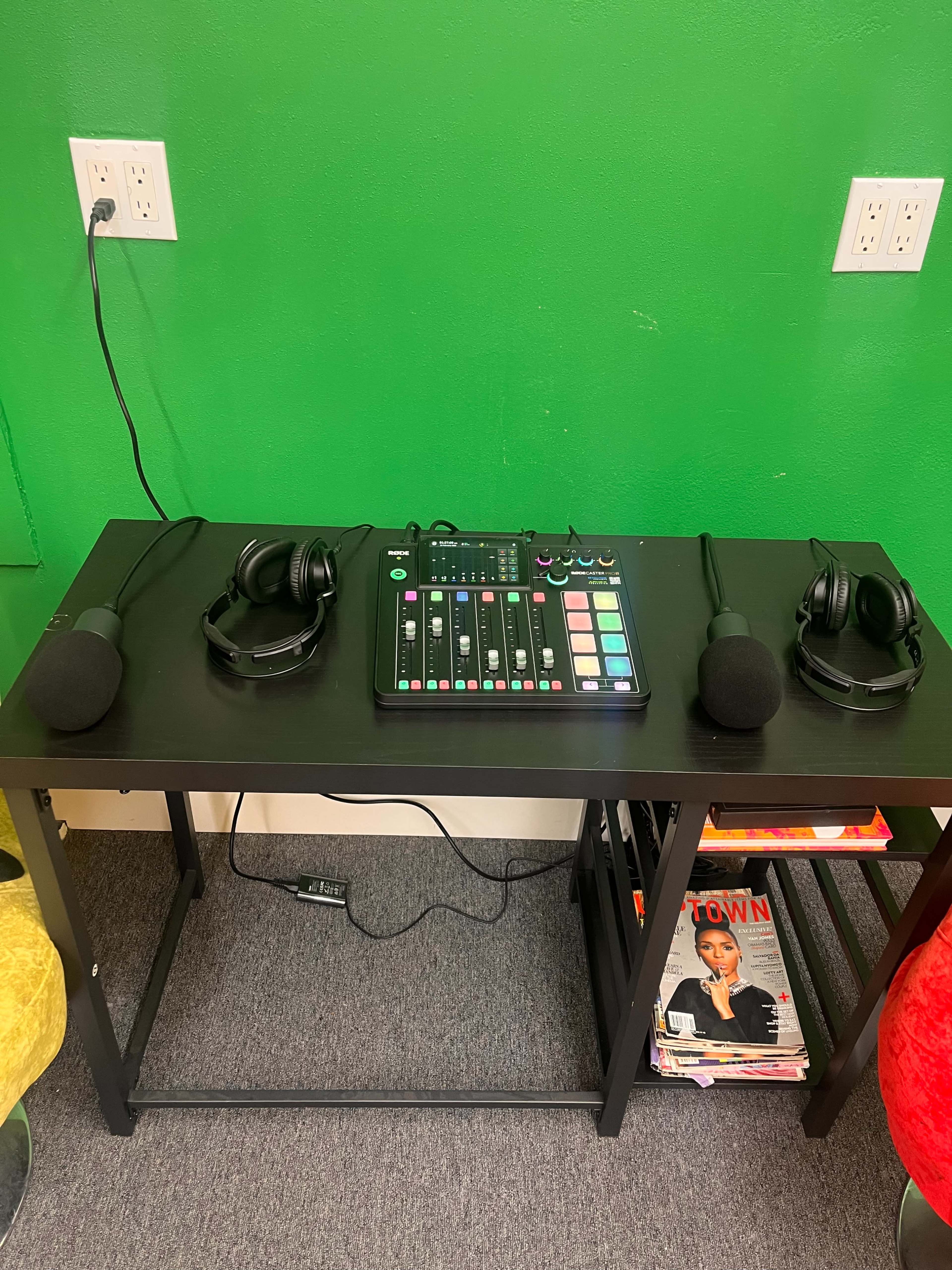 A black table displays a sound mixing console and two sets of headphones, with microphones positioned on either side.