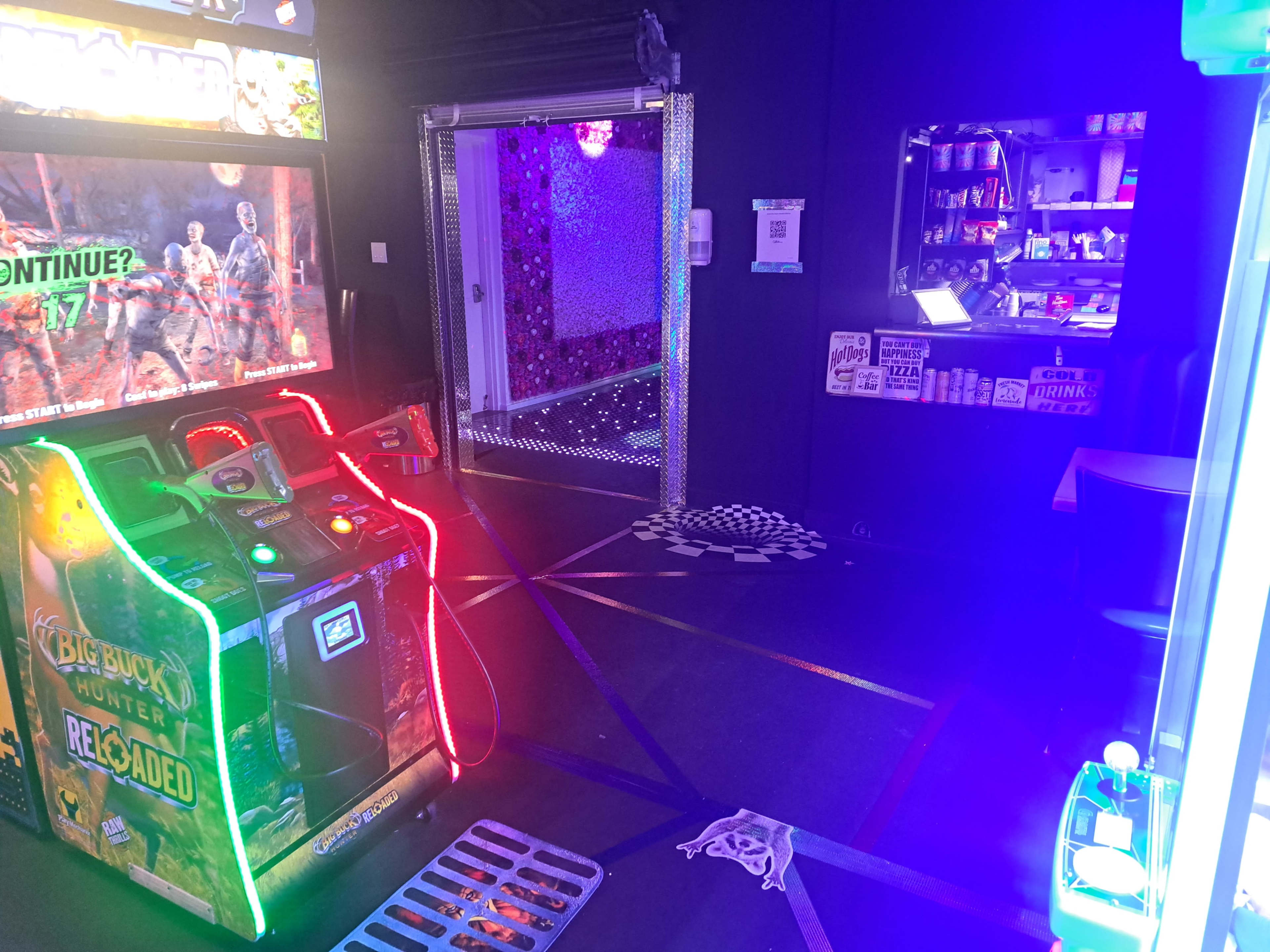 The image shows a brightly lit arcade setup featuring a game machine on the left and a doorway leading to another area in the background.