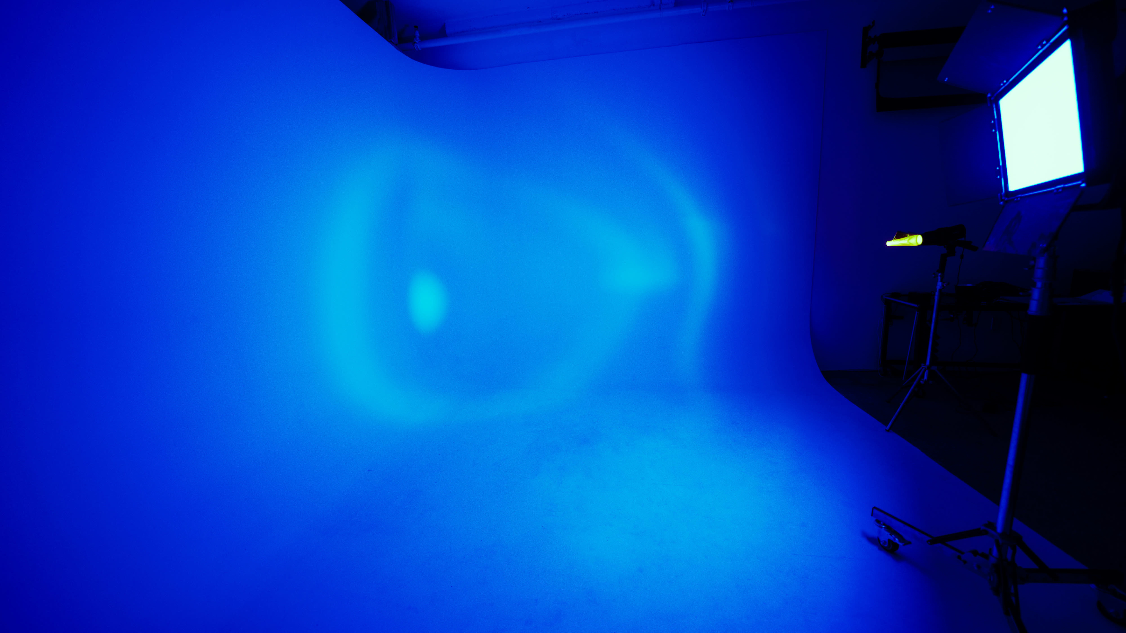 A studio space with a smooth blue backdrop and lighting equipment casting blue light across the scene.
