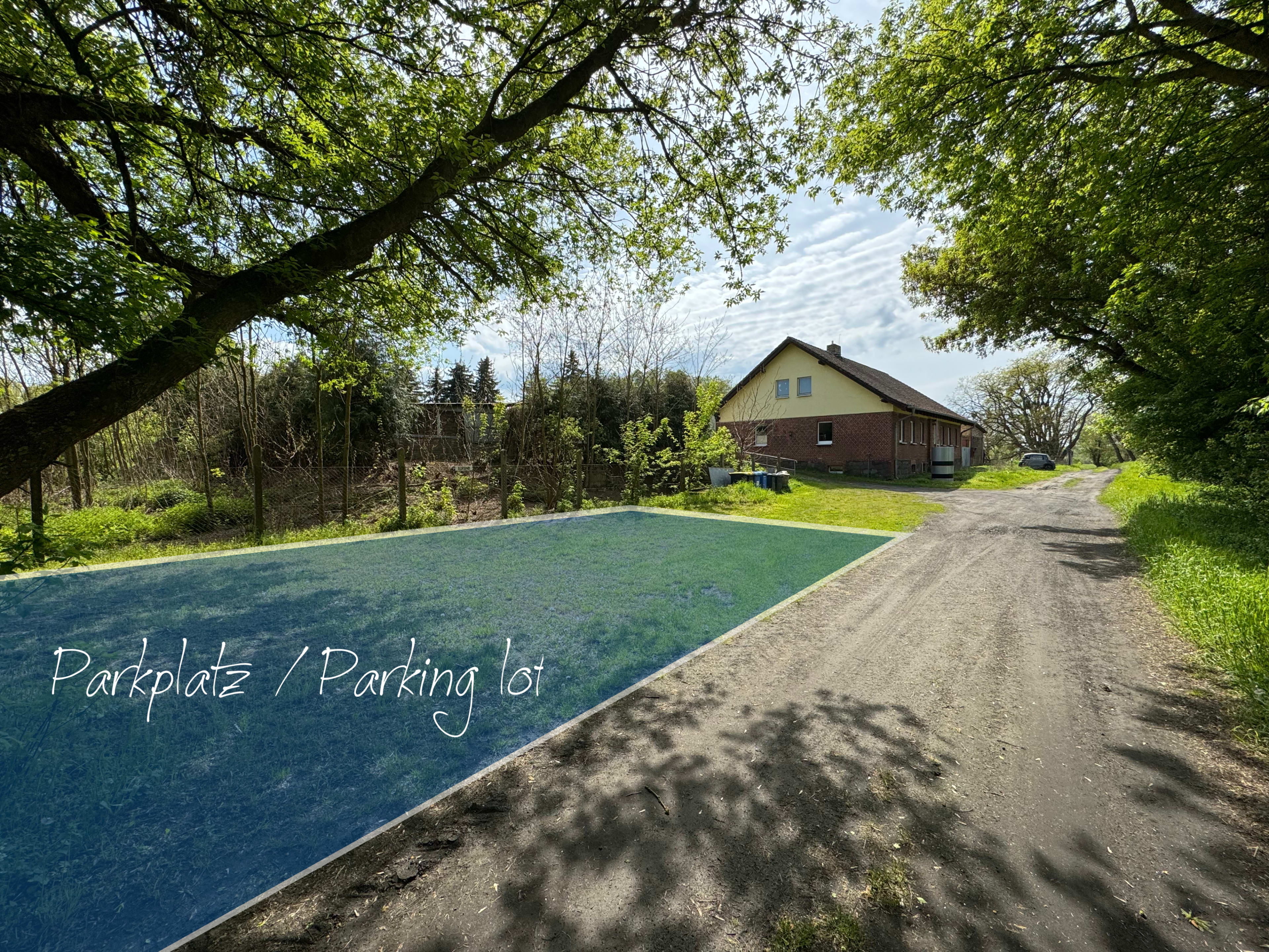 The image shows a parking lot beside a dirt road leading to a two-story house surrounded by greenery.