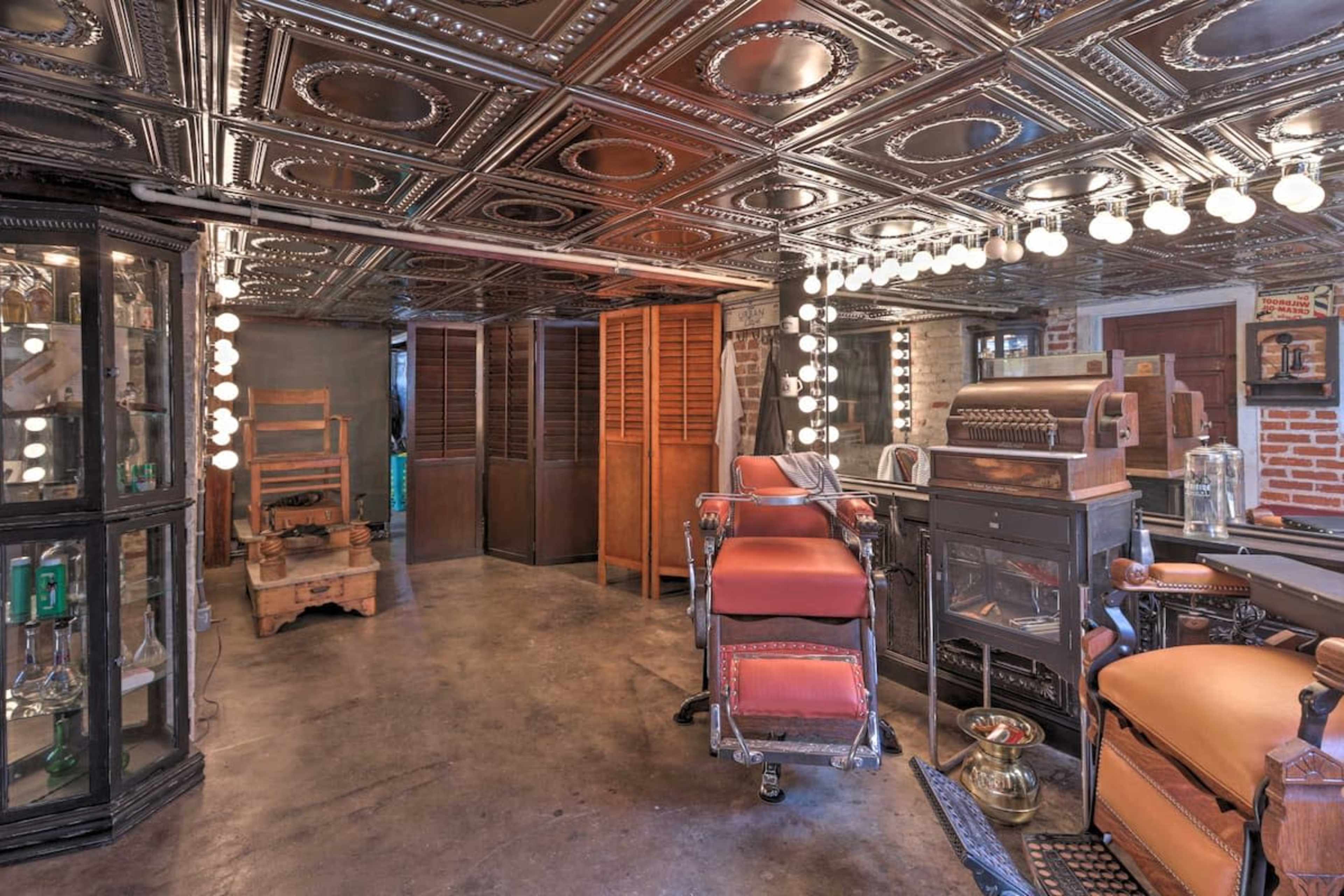 A vintage barber shop interior with a mirrored ceiling, antique furniture, and display cases.