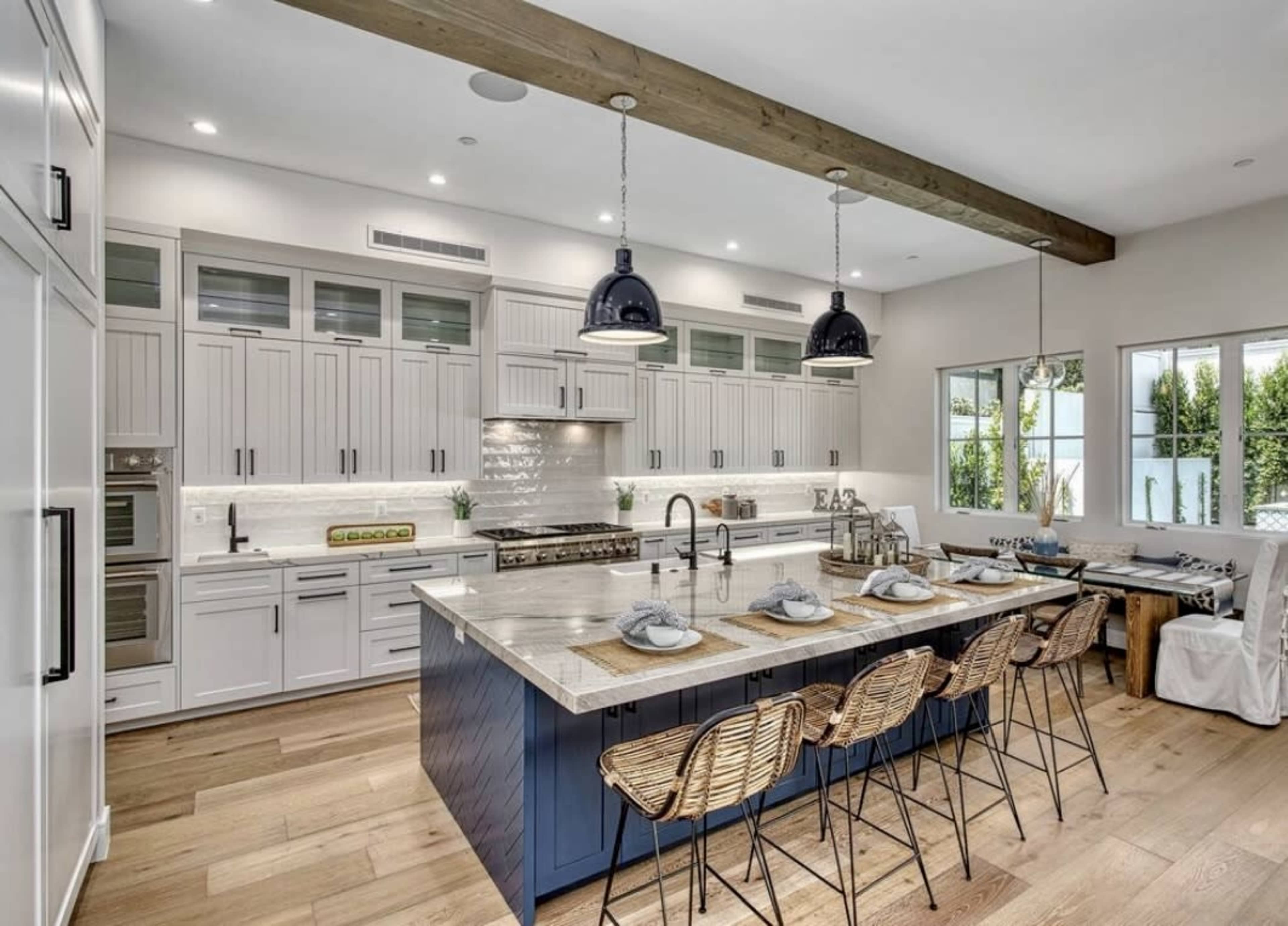 A modern kitchen featuring a large island with seating, stainless steel appliances, and light wood accents.
