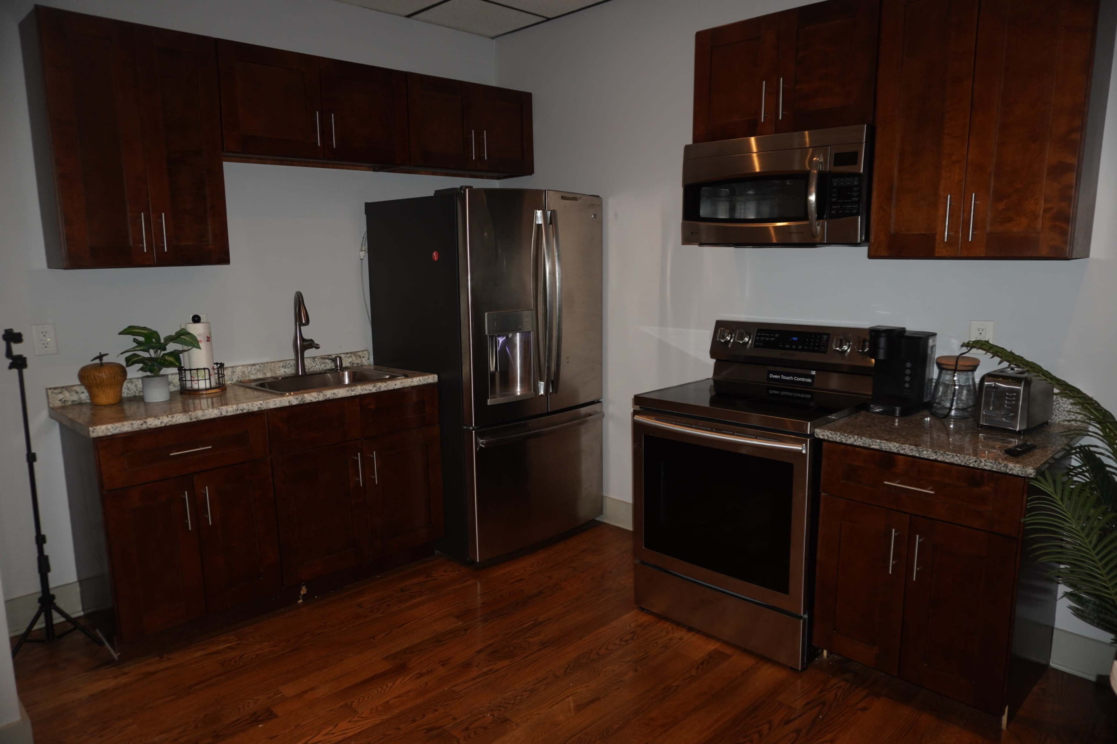 The image shows a modern kitchen with dark wood cabinets, stainless steel appliances, and a granite countertop.