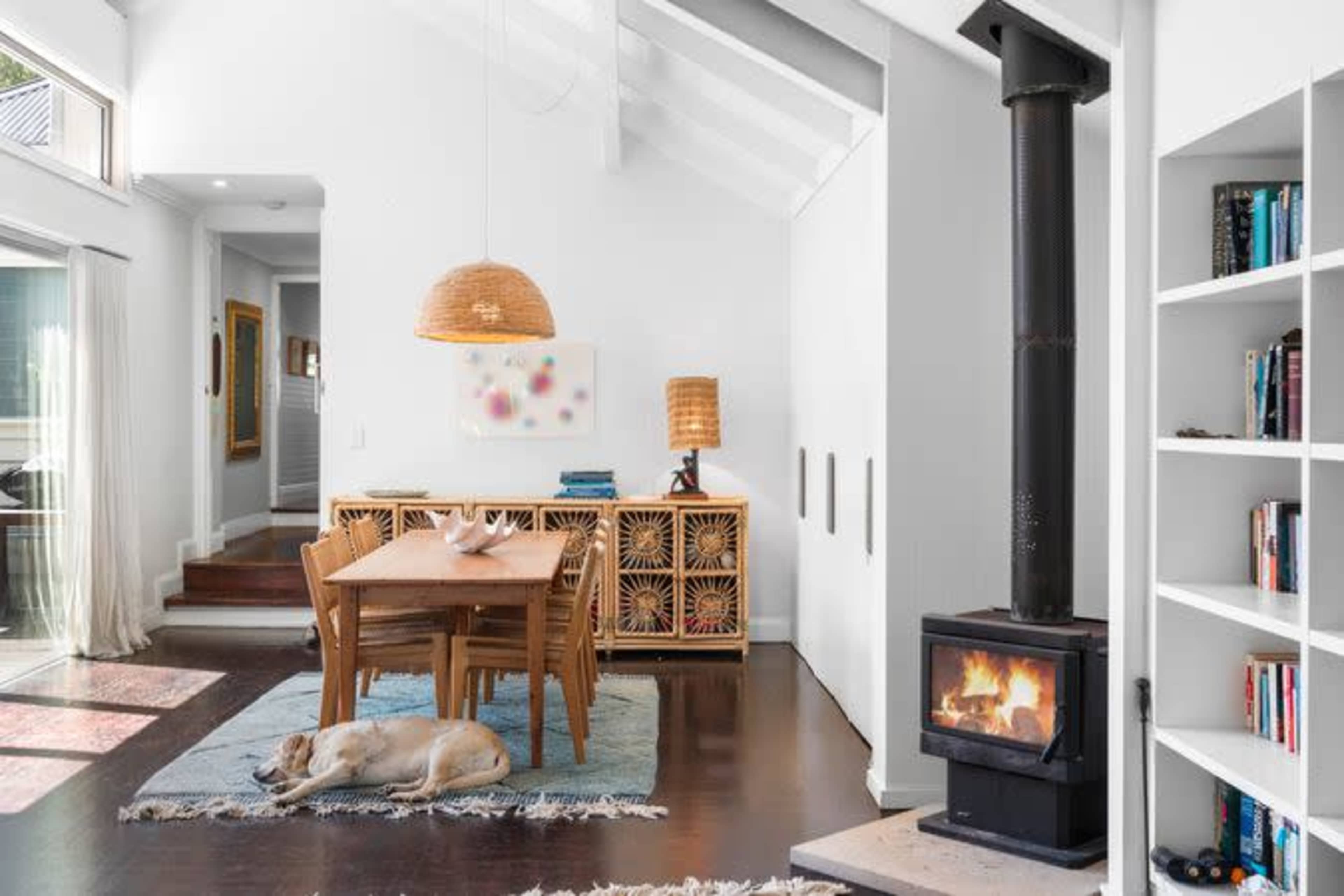 A modern living space with a dining area, a wood-burning stove, and a sleeping dog on a rug.