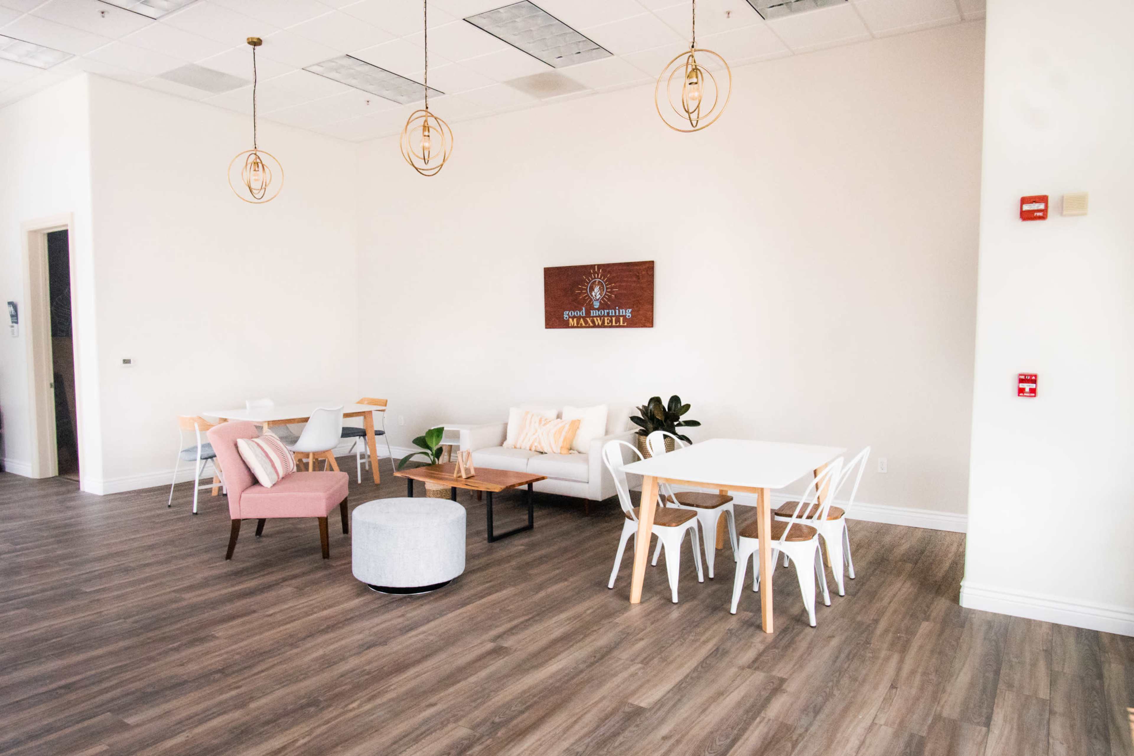 A spacious, well-lit interior with modern furniture, including a seating area with a sofa, chairs, and several tables.