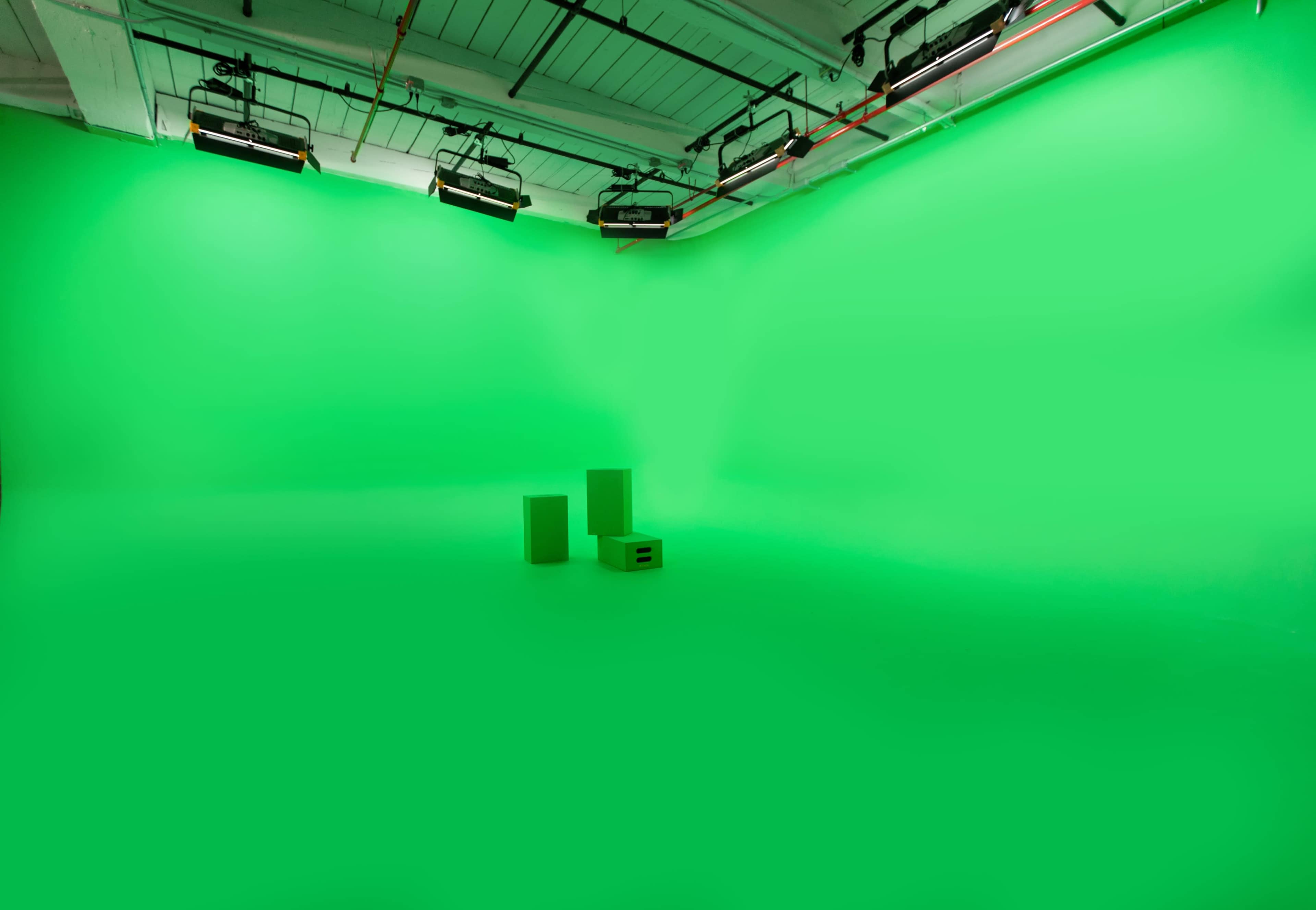 A green screen studio with two green props placed on the floor.