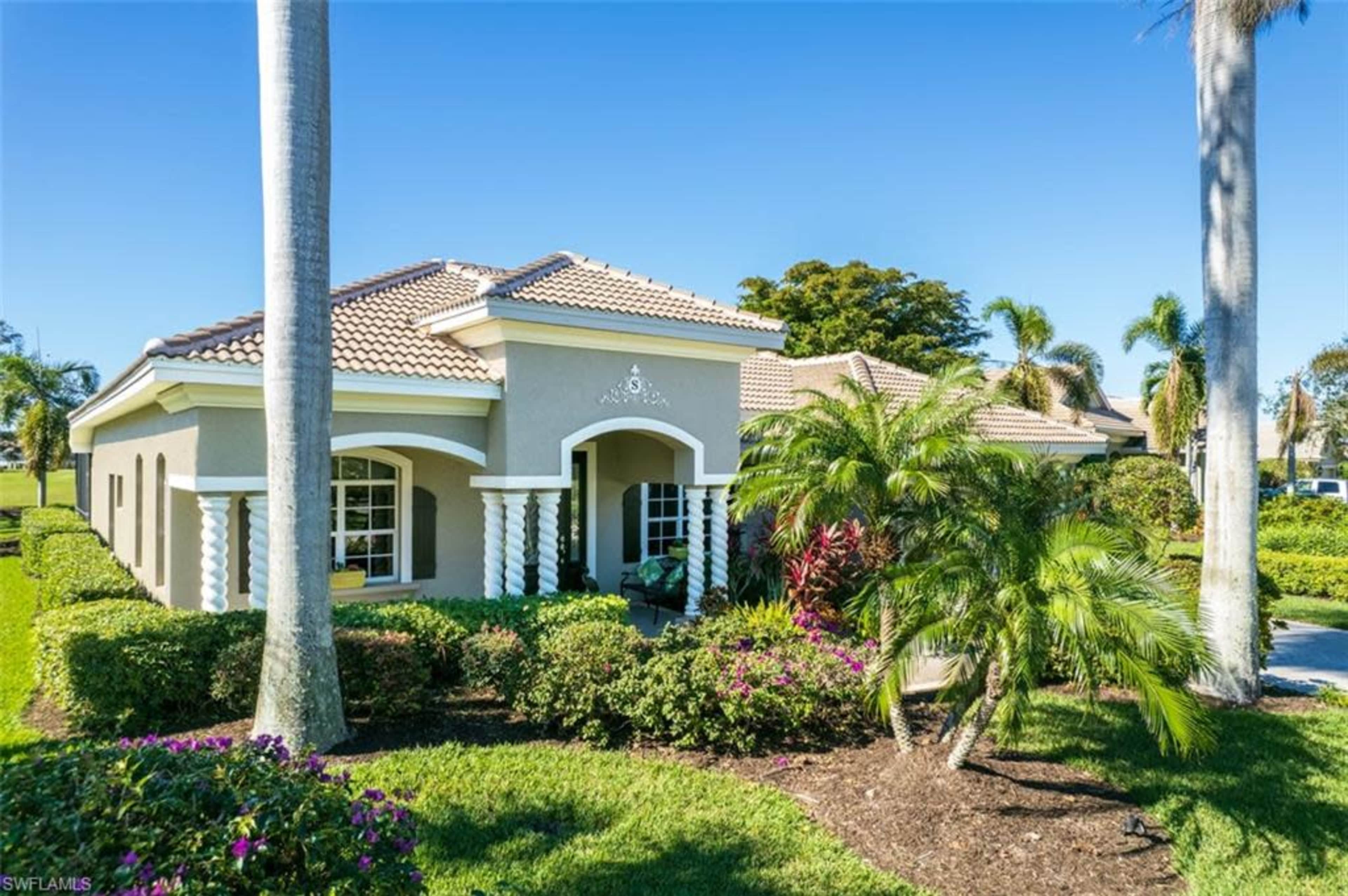 A single-story house with a tiled roof and landscaped garden is situated in a tropical setting.