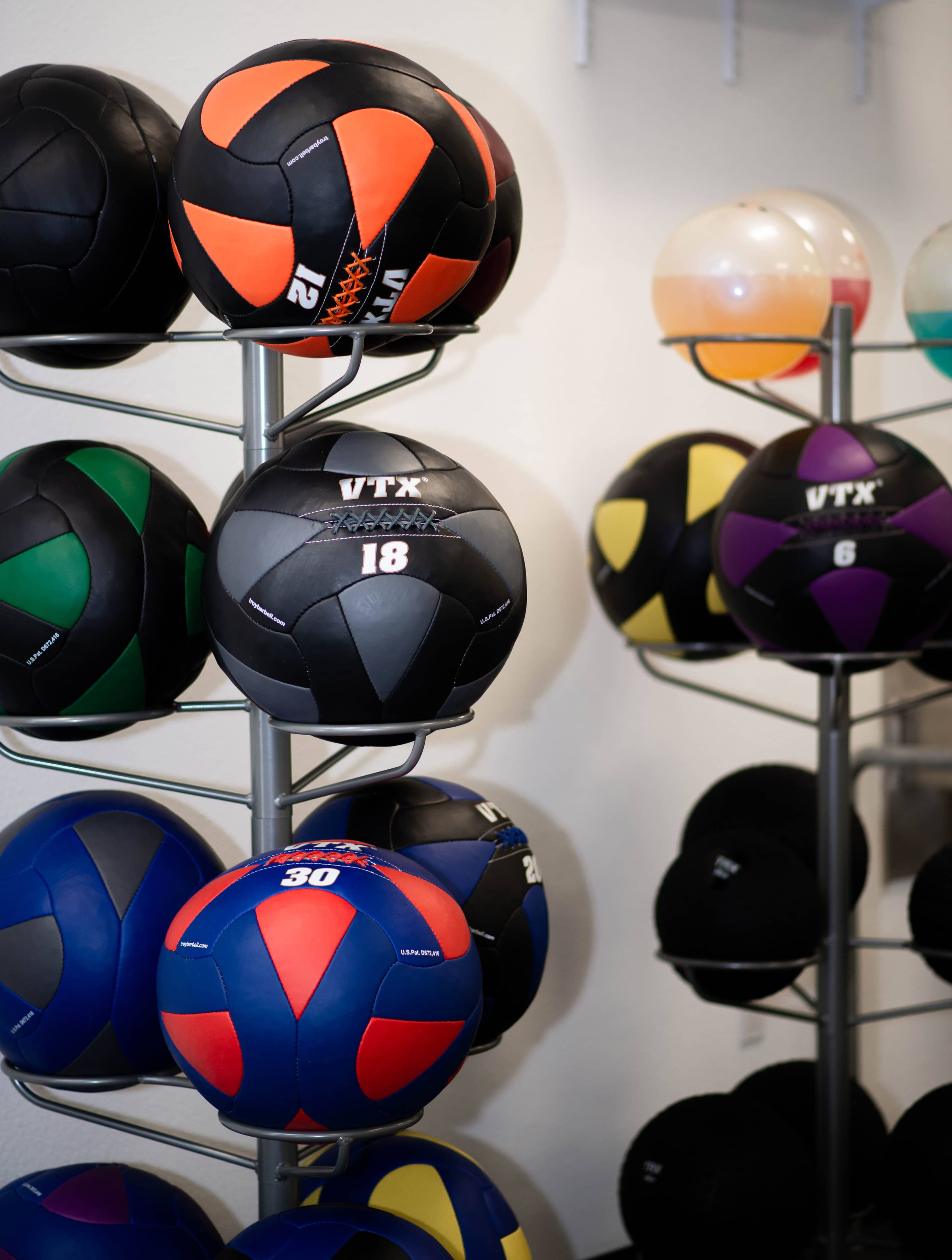 A display of various colored volleyballs and exercise balls organized on multiple racks.