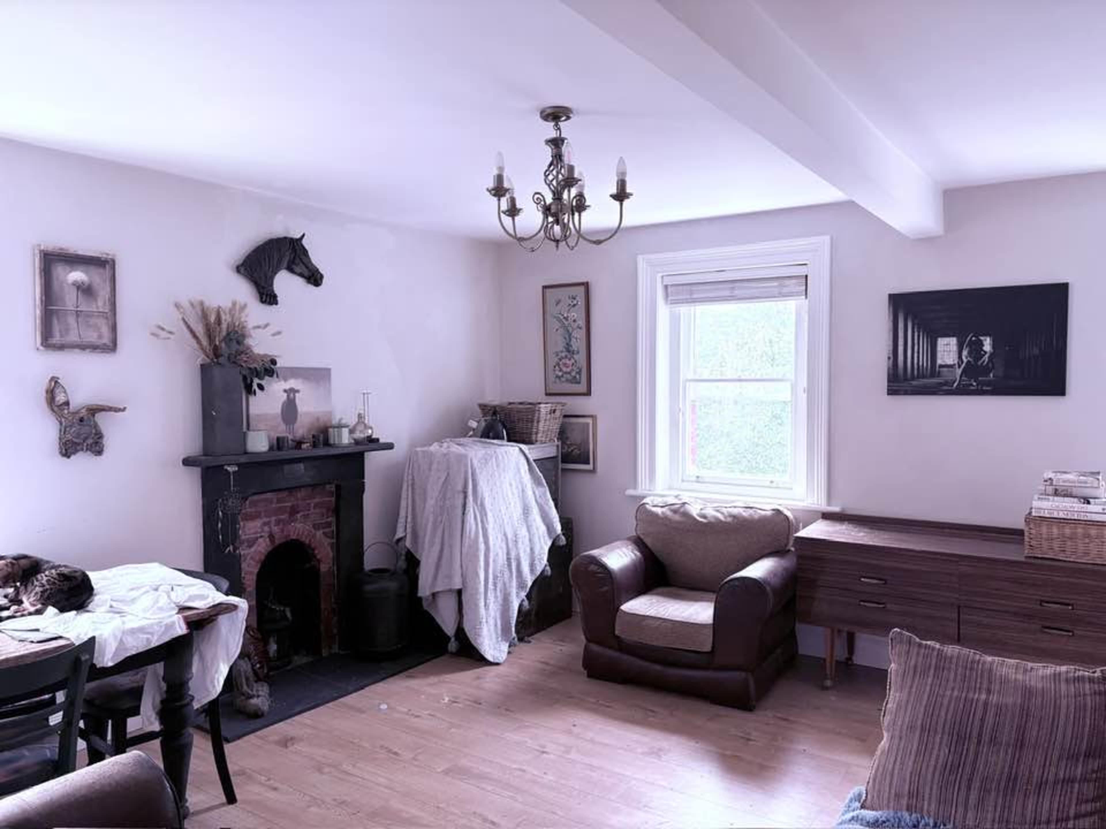 The room features a cozy living space with a fireplace, a chandelier, and a mix of furniture, including a brown armchair and a dining table.