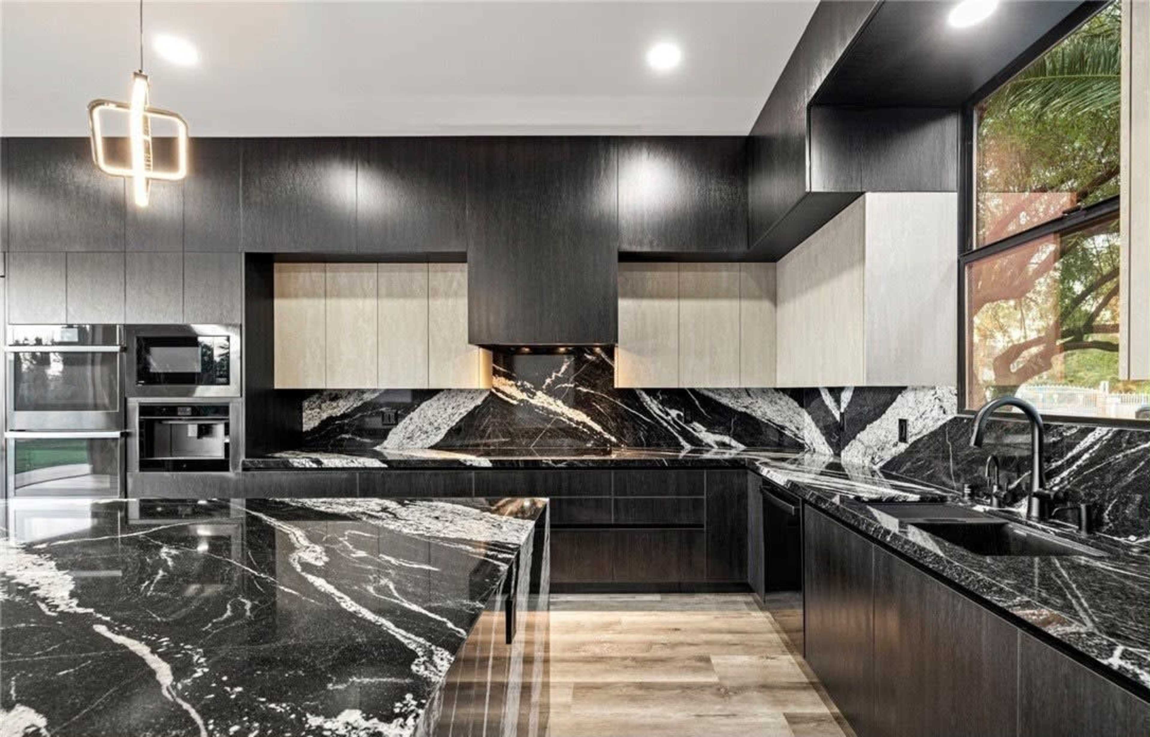 The kitchen features dark cabinets and striking black marble countertops with white veining, complemented by modern appliances.