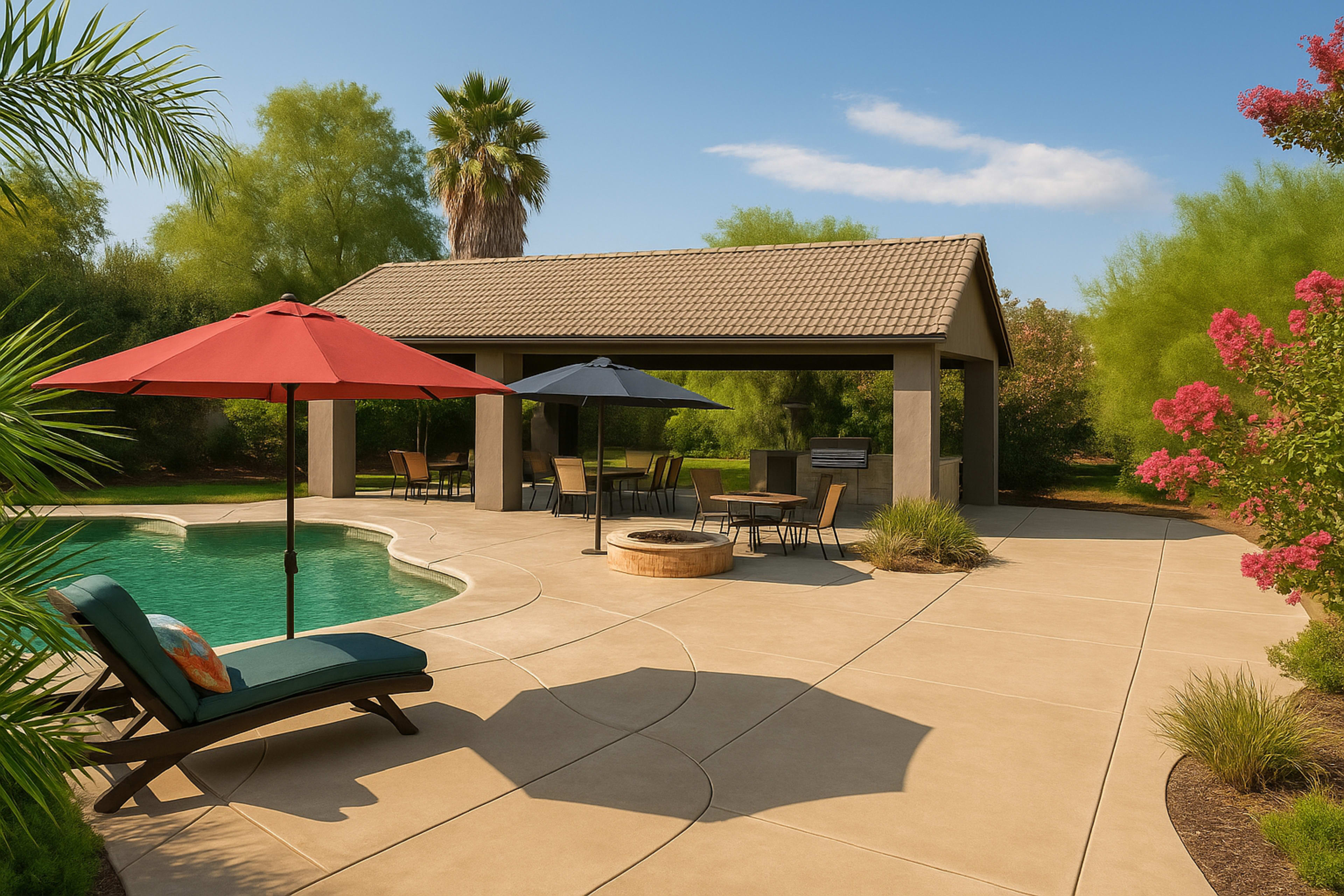 A poolside area features a shaded cabana, two umbrellas, and lounge chairs surrounded by greenery.